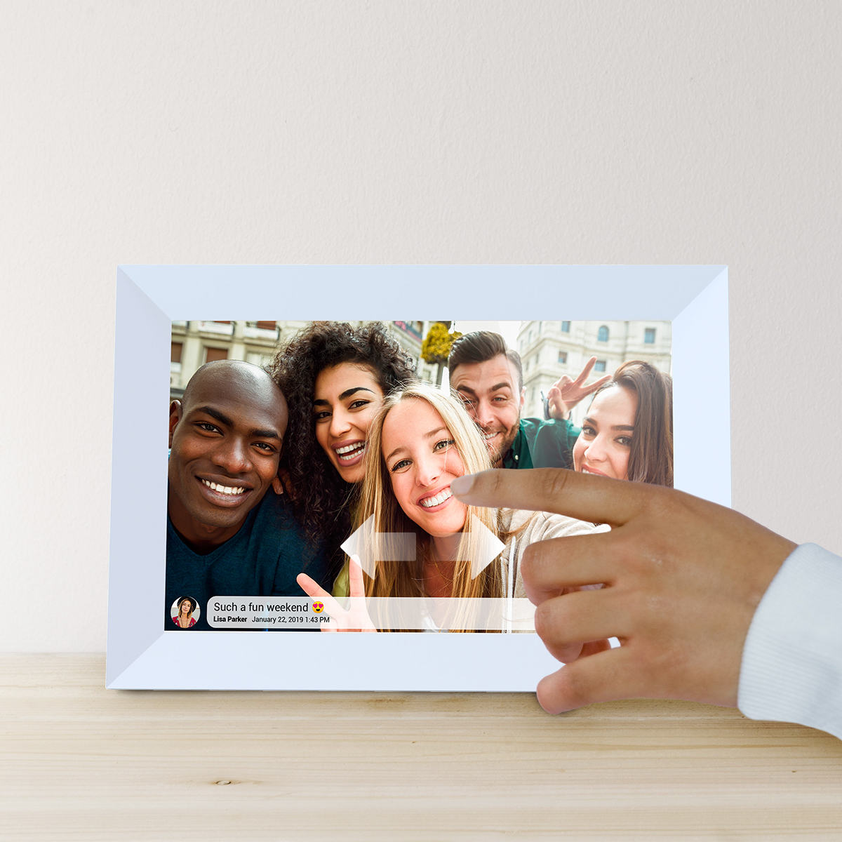 Ręka wskazuje na cyfrową ramkę do zdjęć wyświetlającą selfie grupowe.