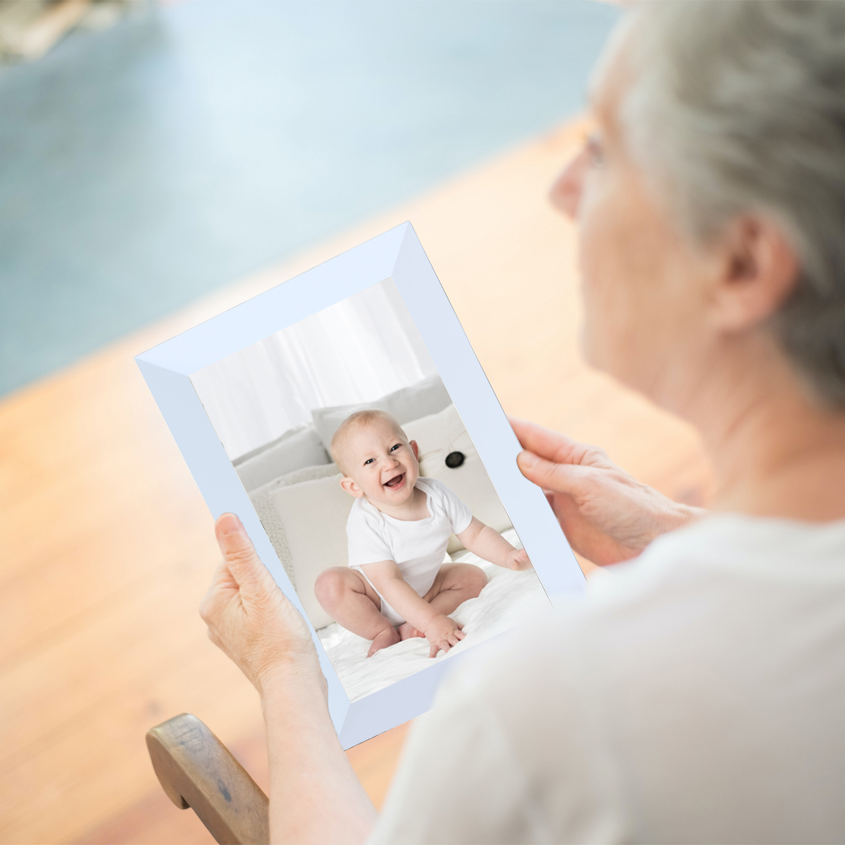 Starsza kobieta trzyma ramkę ze zdjęciem dziecka. Dziecko się uśmiecha.