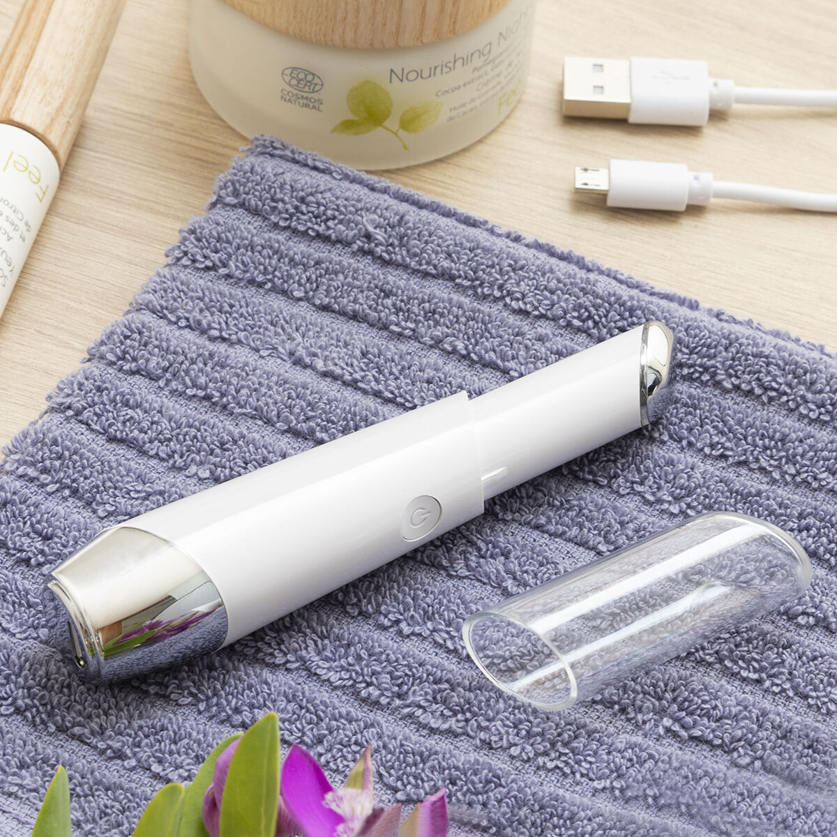 Dispositivo di bellezza bianco, fiala di vetro aperta, su un asciugamano, con crema.