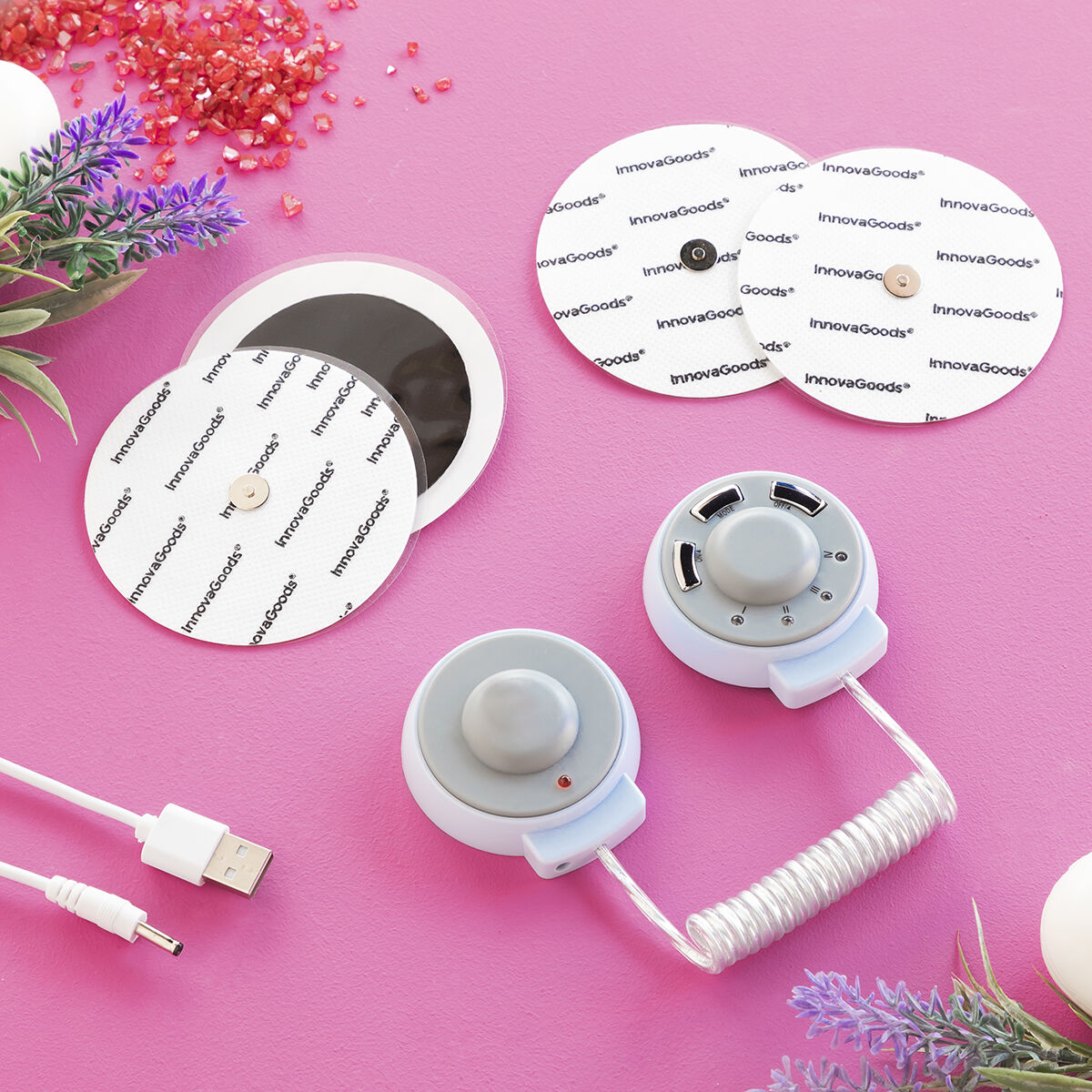 Una vista dall'alto dei prodotti InnovaGoods, tra cui cuscinetti, un controller e un cavo USB, su sfondo rosa.