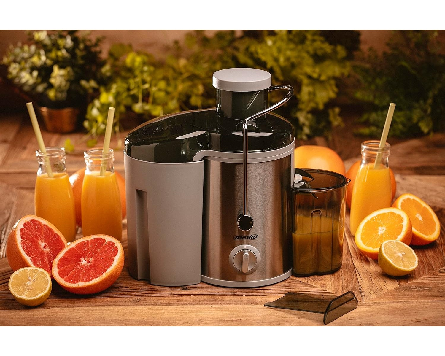 Ein Entsafter mit Saft in Gläsern und Obst drumherum, auf einer Holzoberfläche.