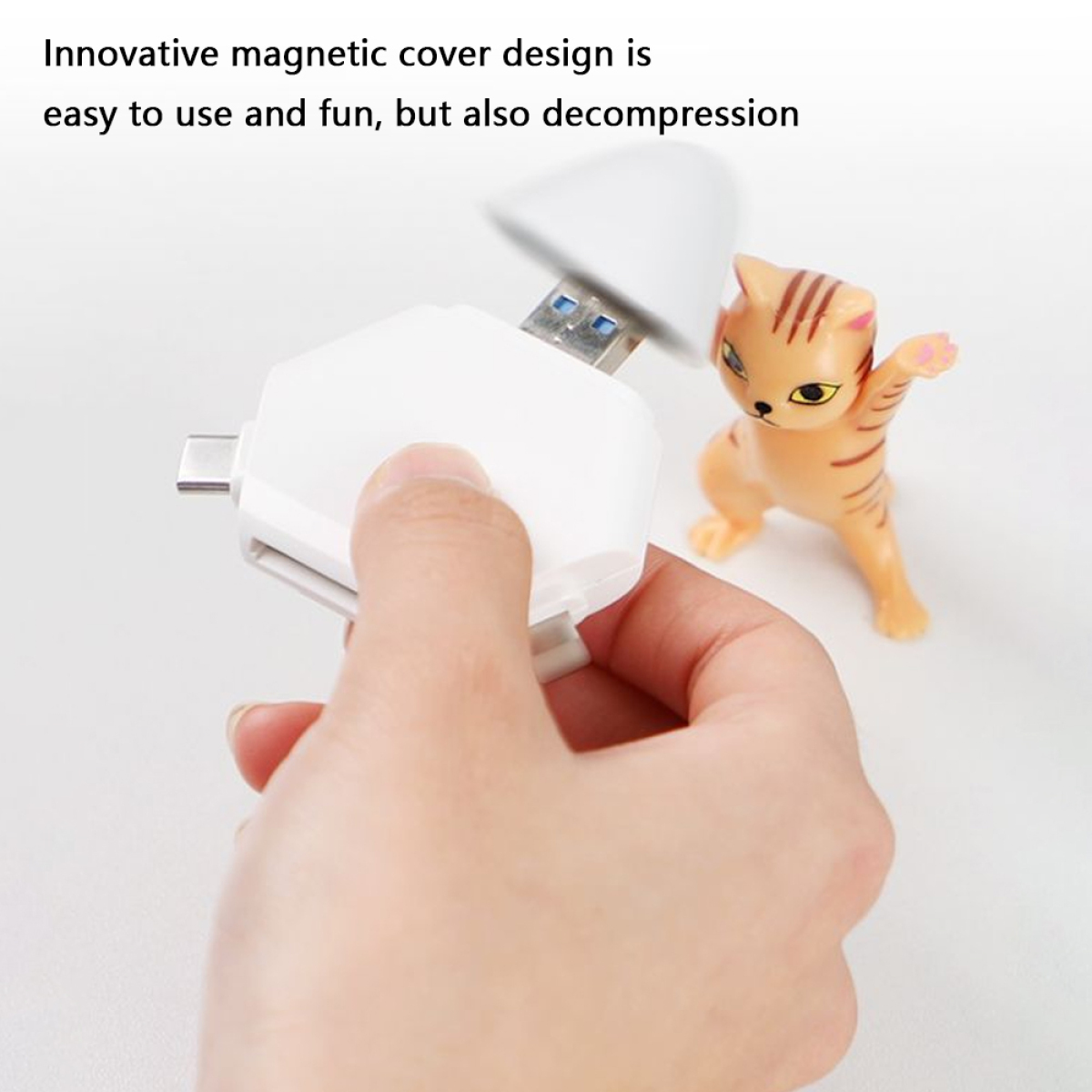 Eine Hand, die einen weißen USB-Adapter hält, mit einer Katzenfigur im Hintergrund.