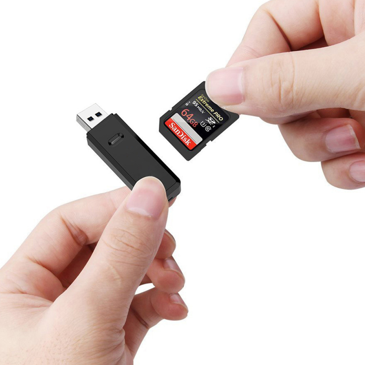 Hände halten einen schwarzen USB-Adapter und eine 64GB Sandisk SD-Karte, weißer Hintergrund.