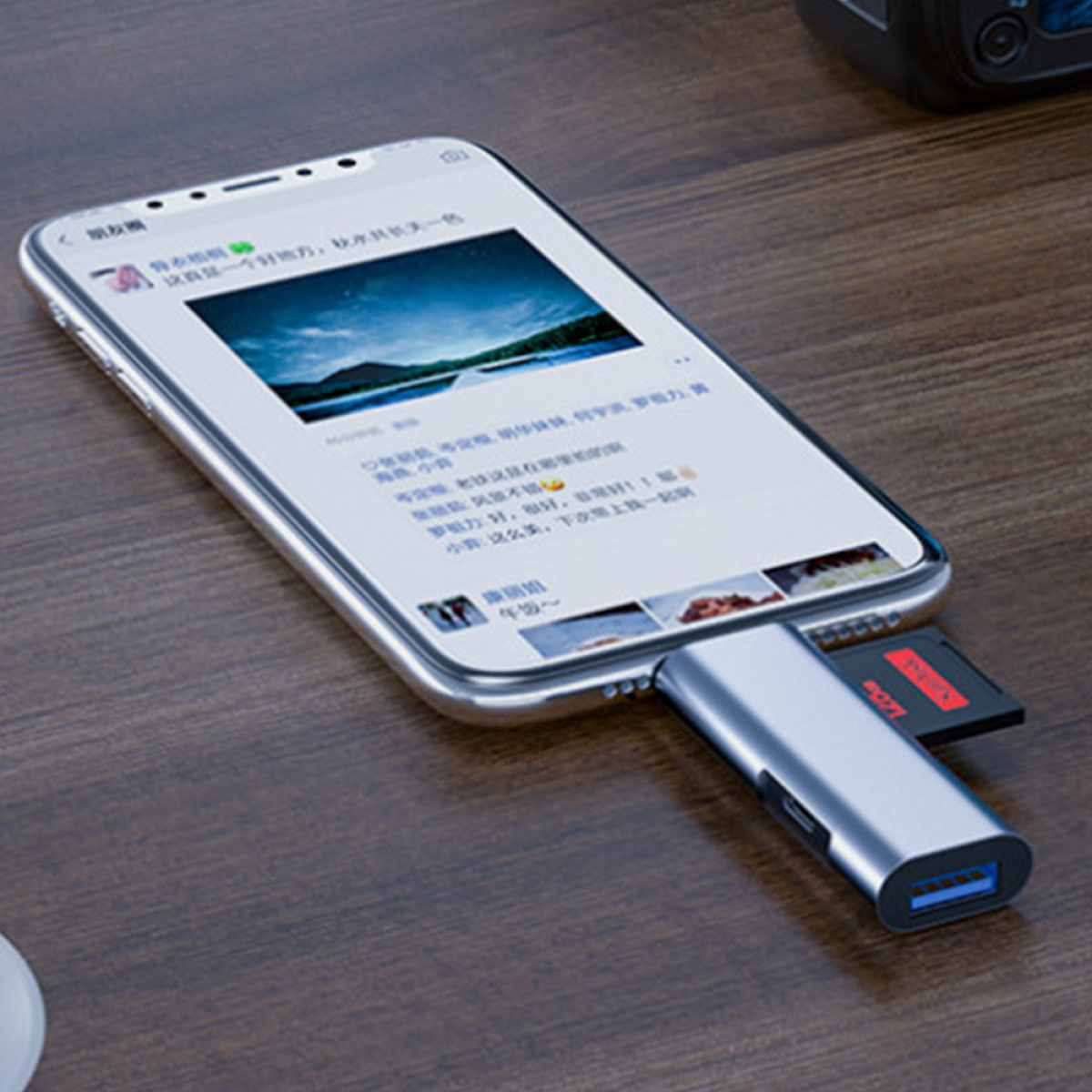 Ein Telefon mit silbernem Hub und USB, Kartenleser, auf einem Holztisch.