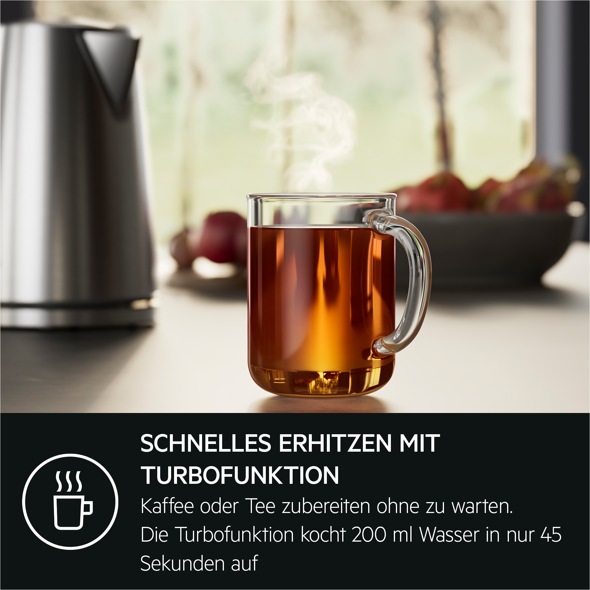 Ein Glas Tee mit aufsteigendem Dampf. Ein Wasserkocher ist im Hintergrund.