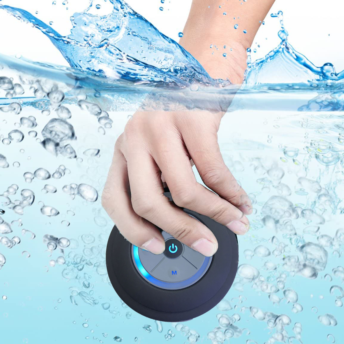 Eine Hand taucht einen schwarzen wasserdichten Lautsprecher in klares Wasser mit Blasen ein.