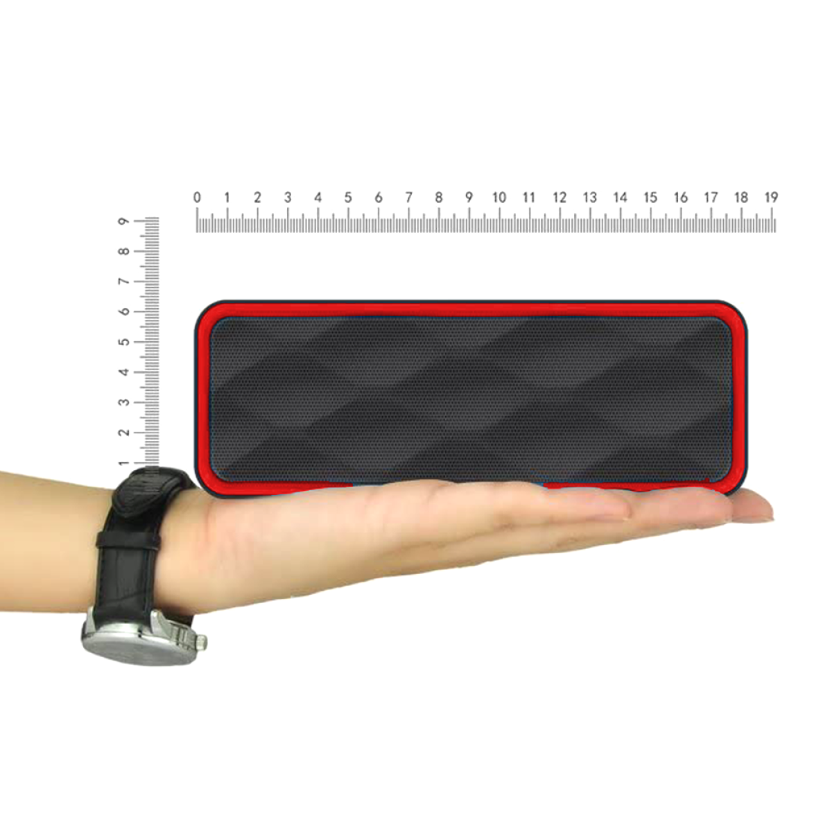 Eine Hand, die einen schwarz-roten Lautsprecher neben einem Lineal hält.