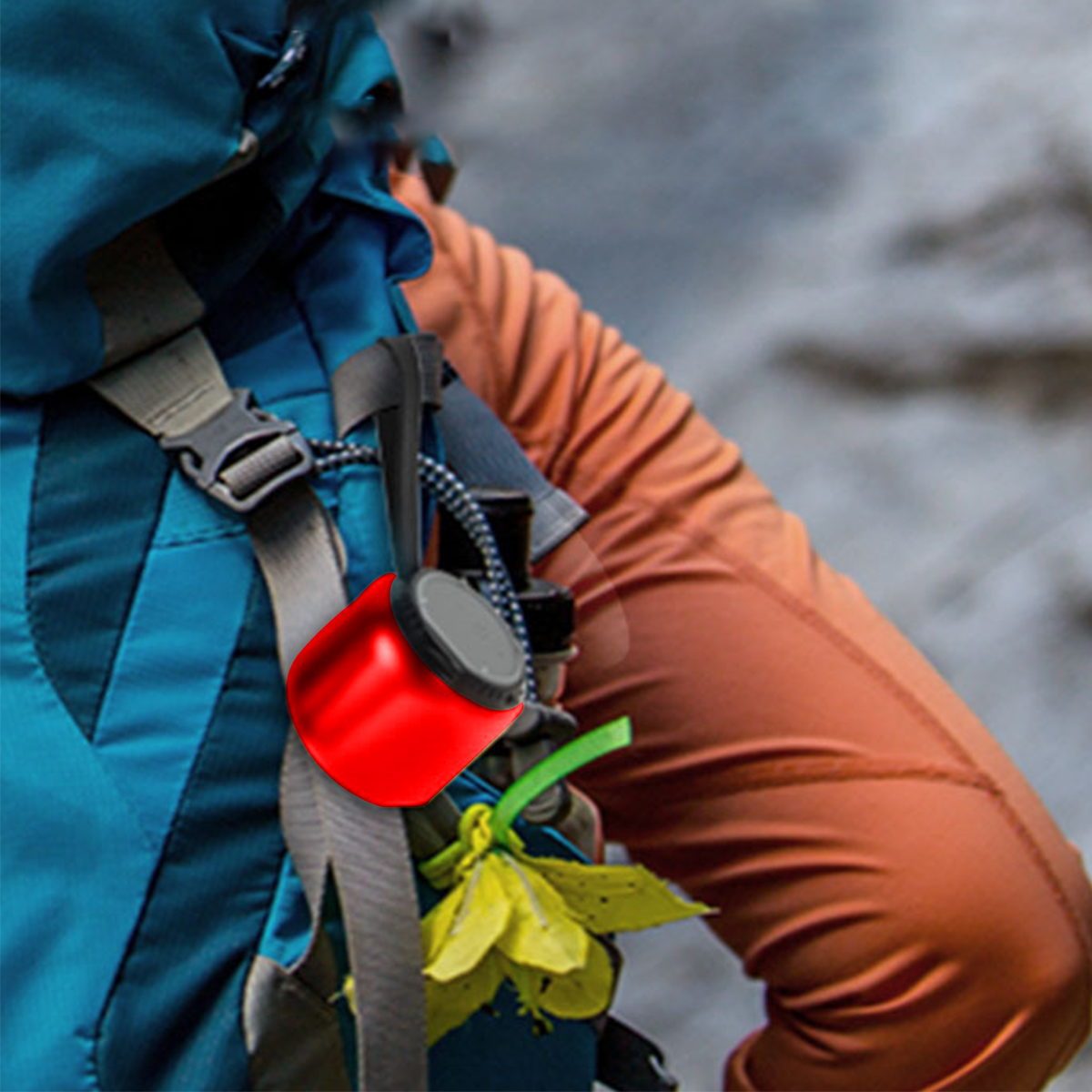 Ein roter Kletterchalkbag an einem blau-orangen Rucksack befestigt.