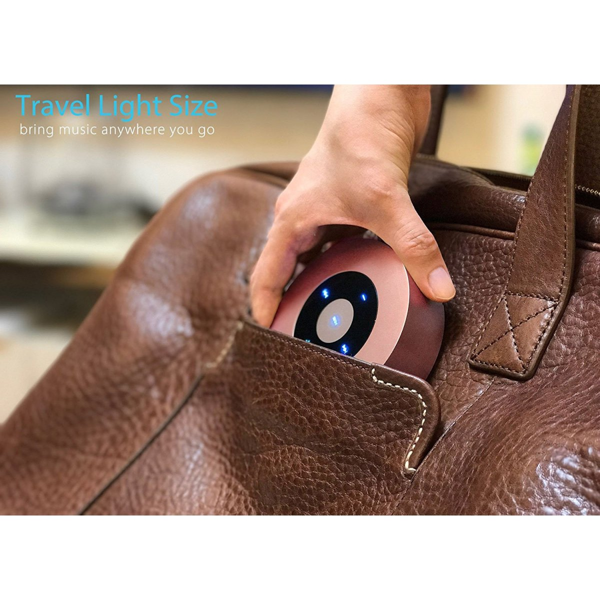 Hand, die einen kleinen Lautsprecher in eine braune Tasche steckt, mit Text: "Travel Light Size".