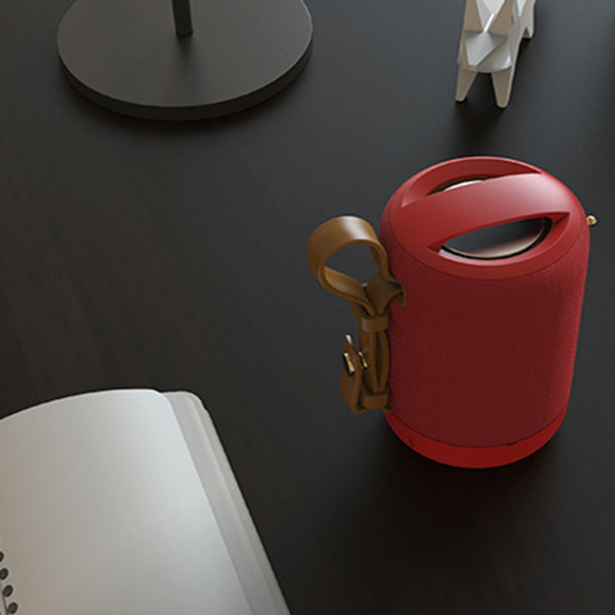 Roter Lautsprecher mit braunem Griff. Weißes Papier und schwarzer Tisch, schwarzer Hintergrund.