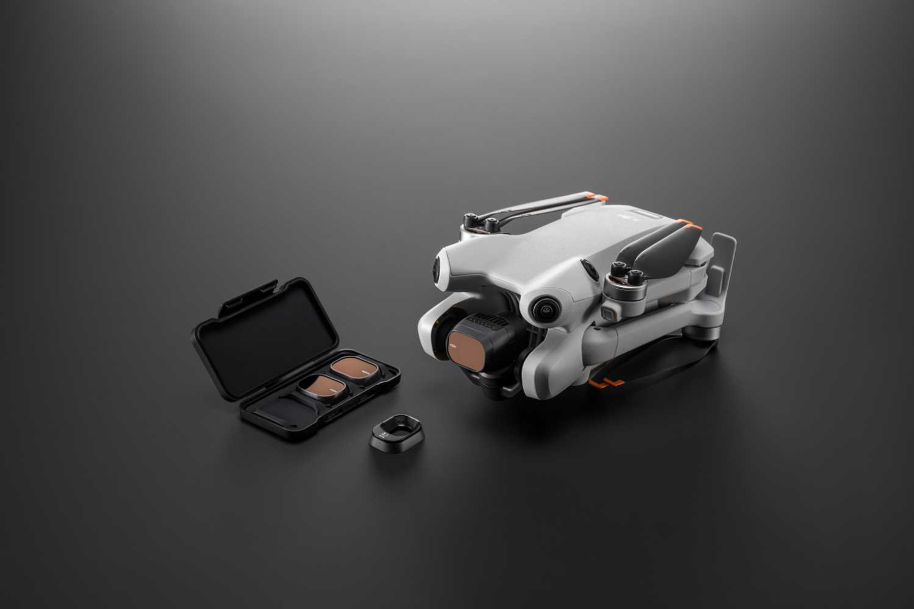 Dron blanco y gris con accesorios sobre superficie gris oscuro.