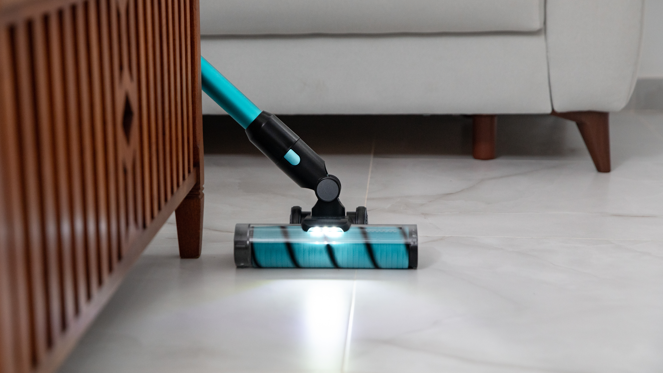 Una testina per aspirapolvere che pulisce un pavimento accanto a un mobile in legno.