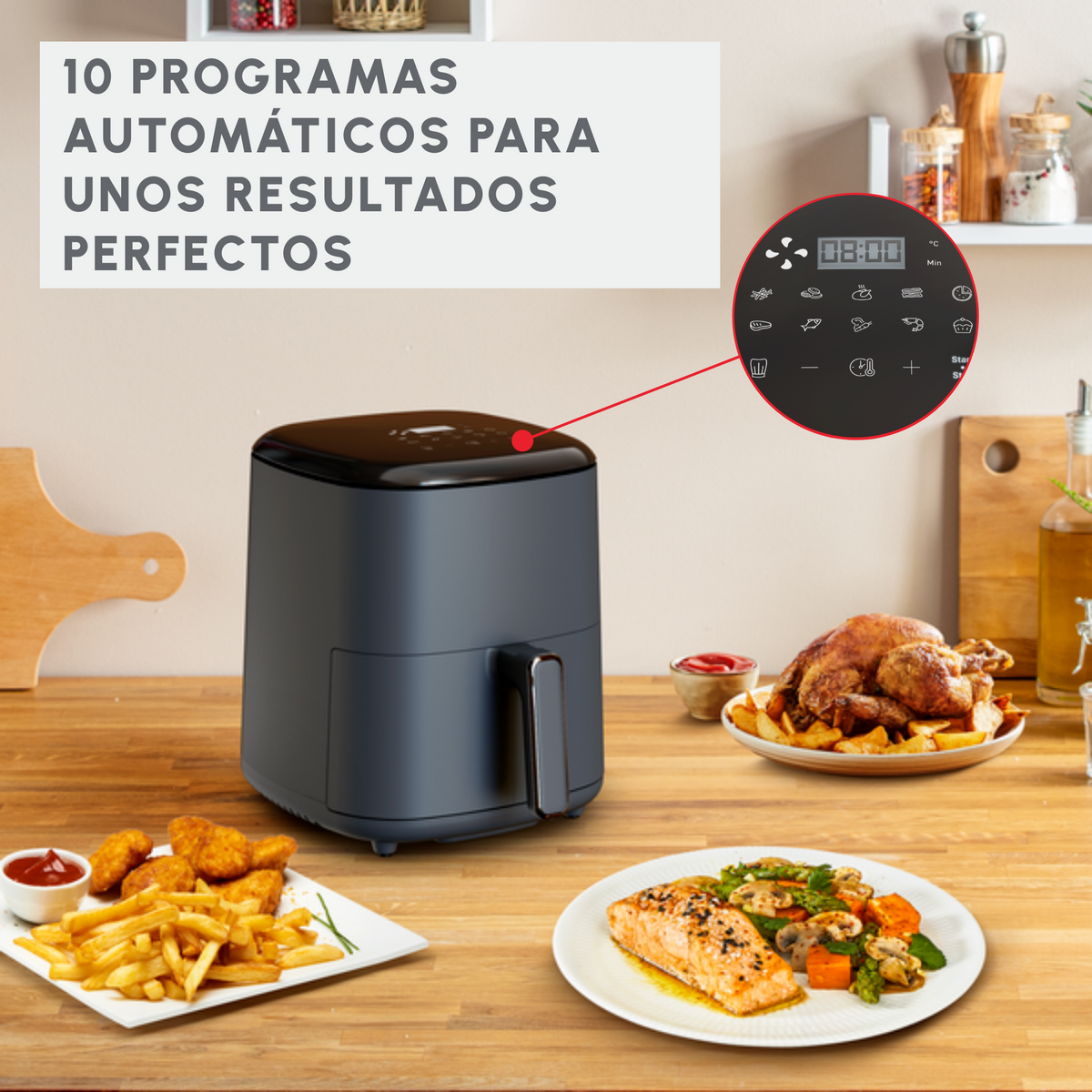 Frytownica powietrzna z wyświetlaczem, jedzenie na talerzach i tekst po hiszpańsku, na drewnianym stole.