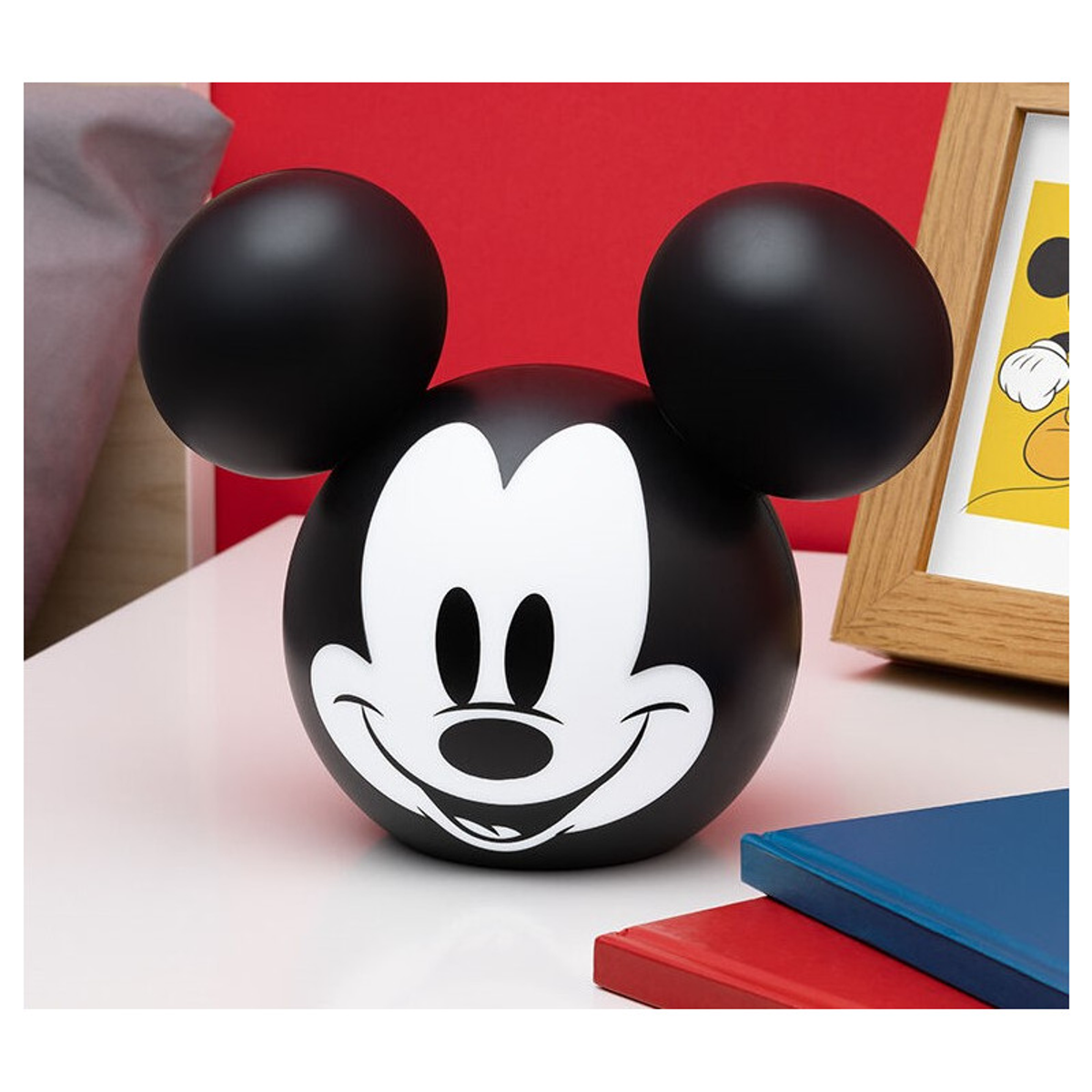 Lámpara con forma de cabeza de Mickey Mouse sobre una superficie blanca, libros.