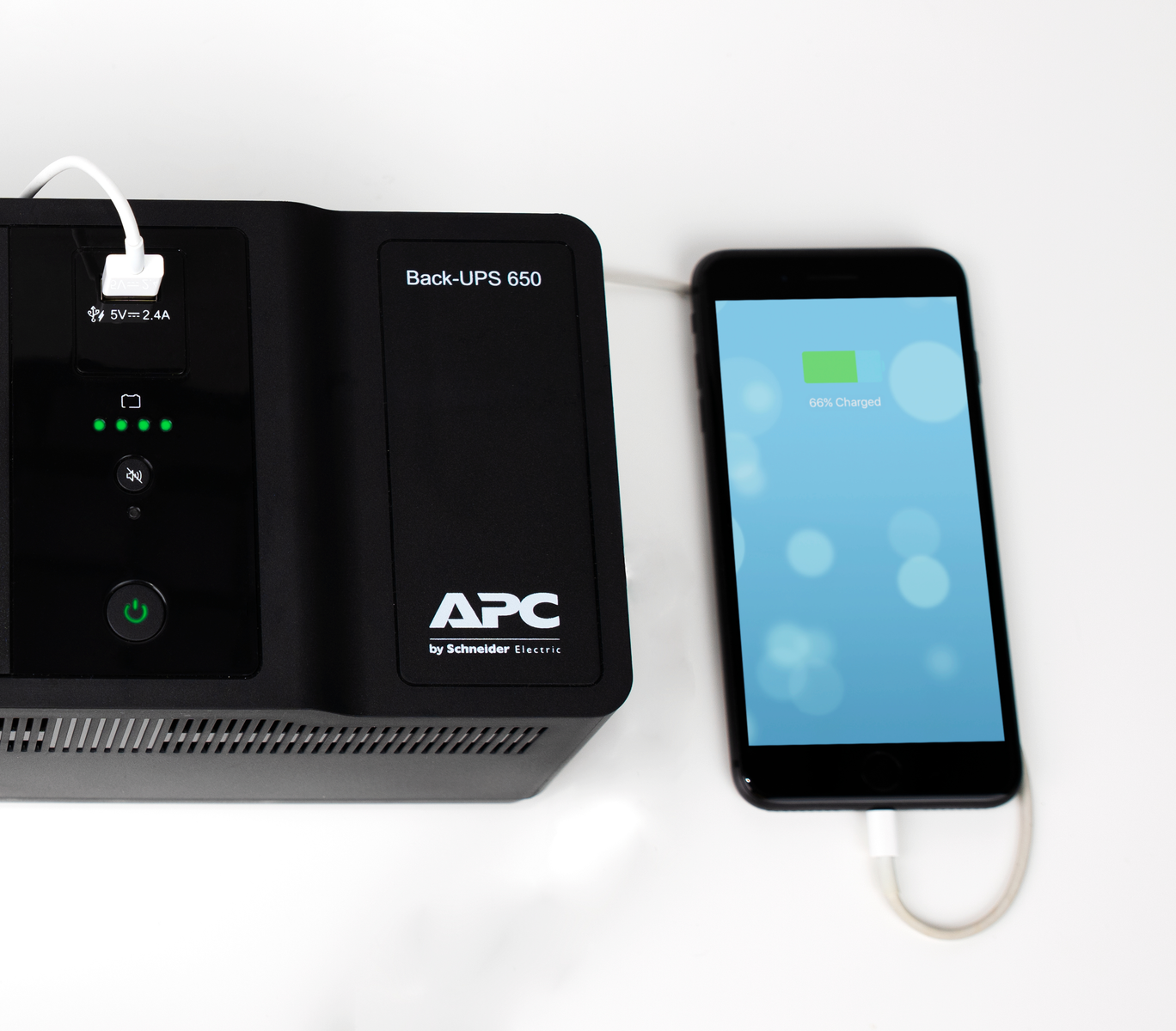 Un gruppo di continuità APC nero è collegato a uno smartphone. Lo schermo del telefono mostra una batteria carica al 66%.