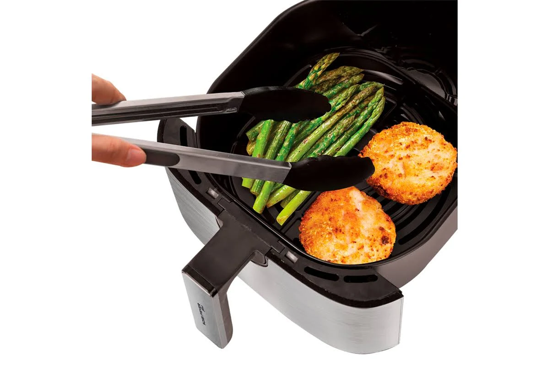 Friggitrice ad aria con cibo. Asparagi e cibo impanato vengono tolti con le pinze.
