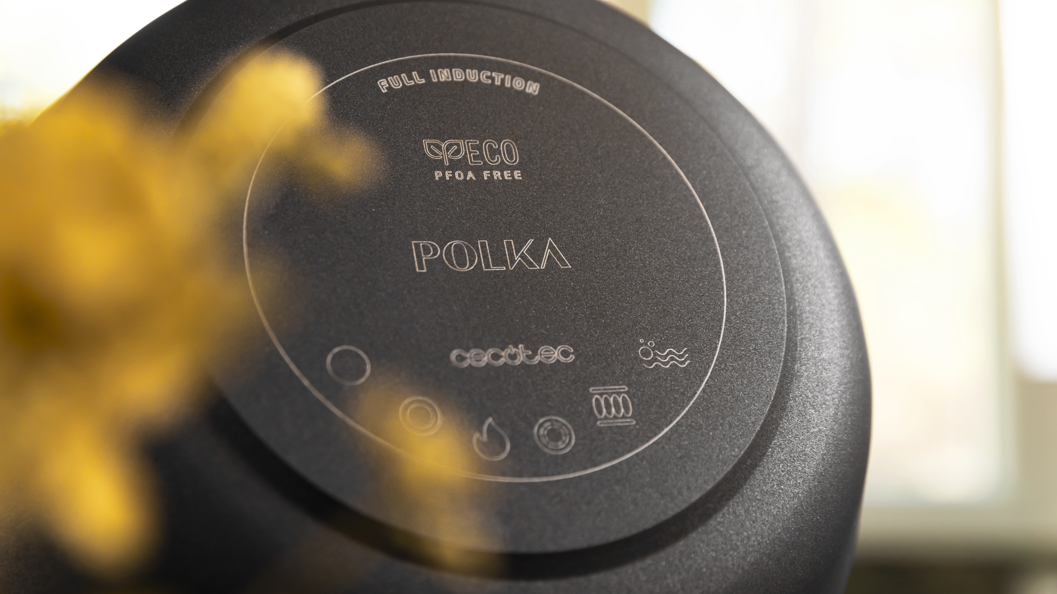 Primer plano de la parte inferior de una sartén negra con la palabra 'Polka' y algunos iconos.