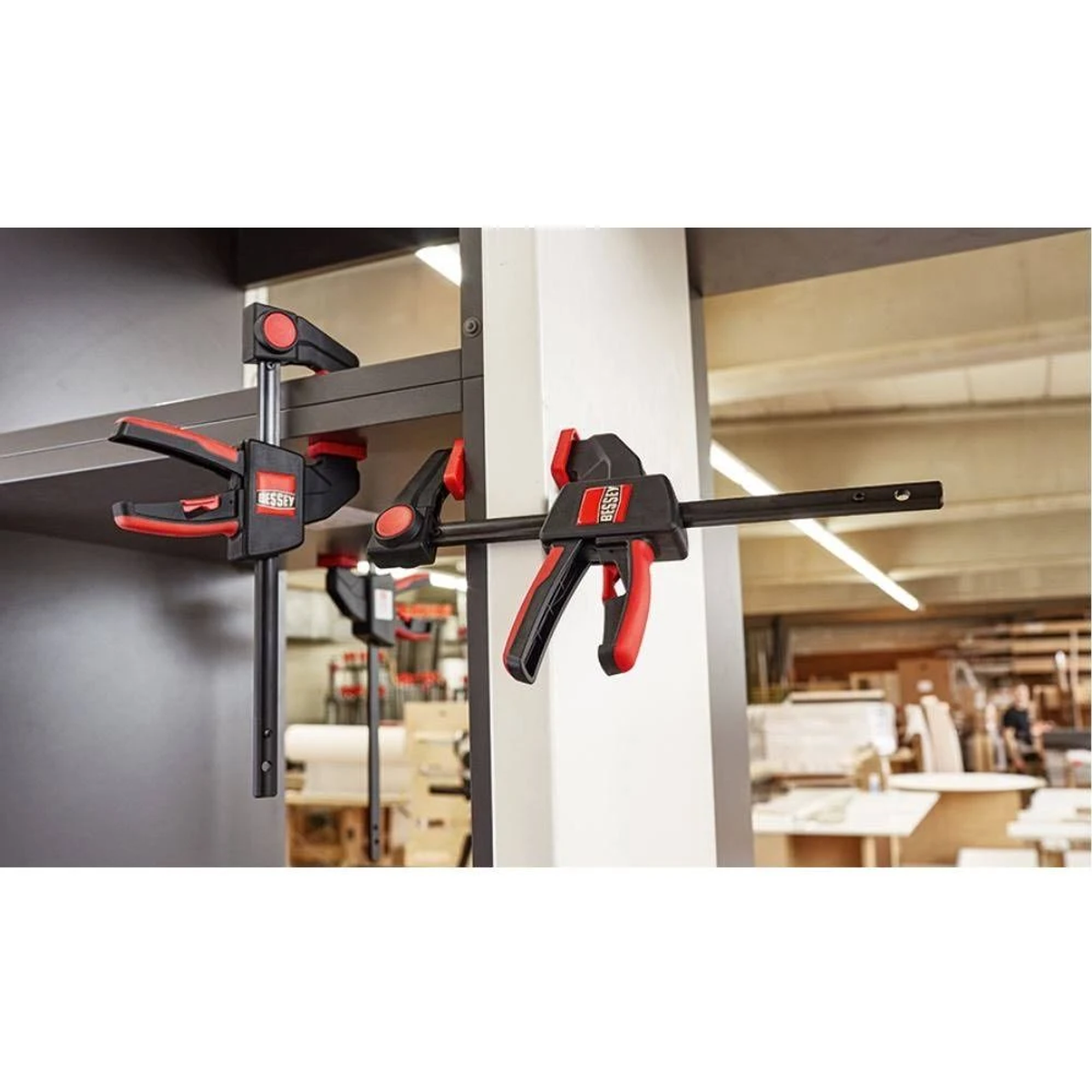 Clamps on a wooden shelf, in a workshop setting. Red and black.