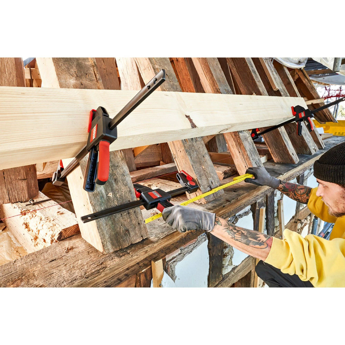 A person using clamps to secure wooden beams.