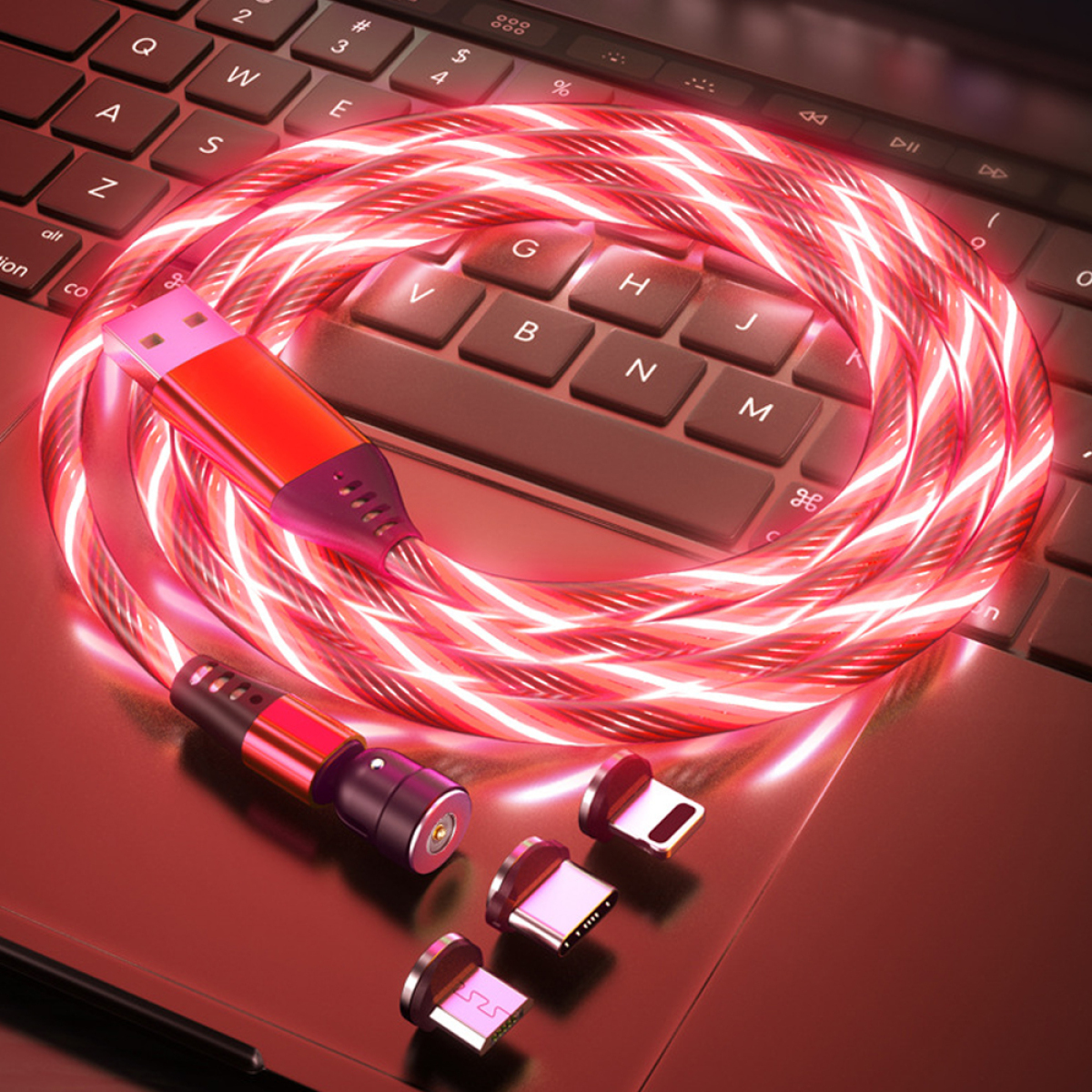 Rotes USB-Kabel mit mehreren Anschlüssen und rotem Ladekopf auf einem Laptop. Dunkler Hintergrund.