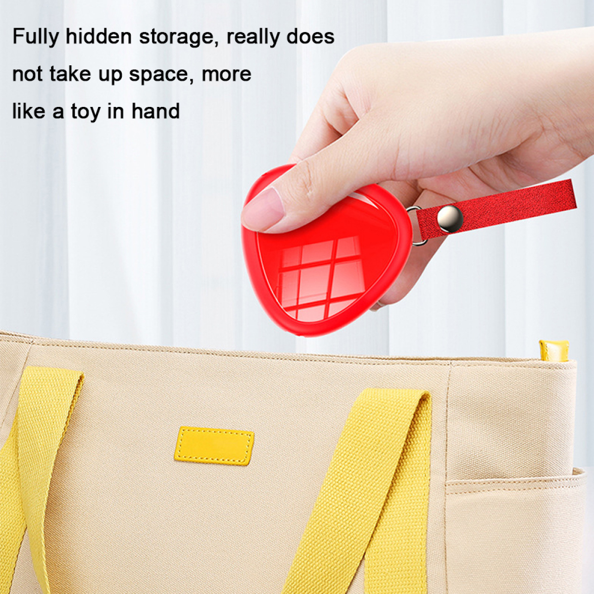 Eine Hand hält ein rotes herzförmiges Objekt. Im Hintergrund eine Tasche mit gelben Akzenten.