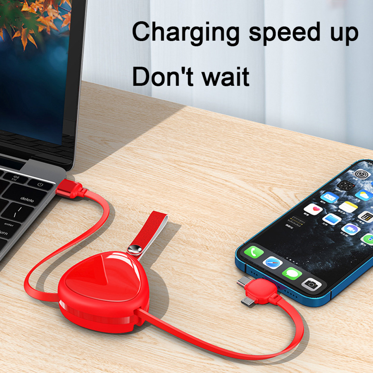 Ein rotes Ladekabel, das mit einem Laptop und einem Telefon auf einem Holztisch verbunden ist.