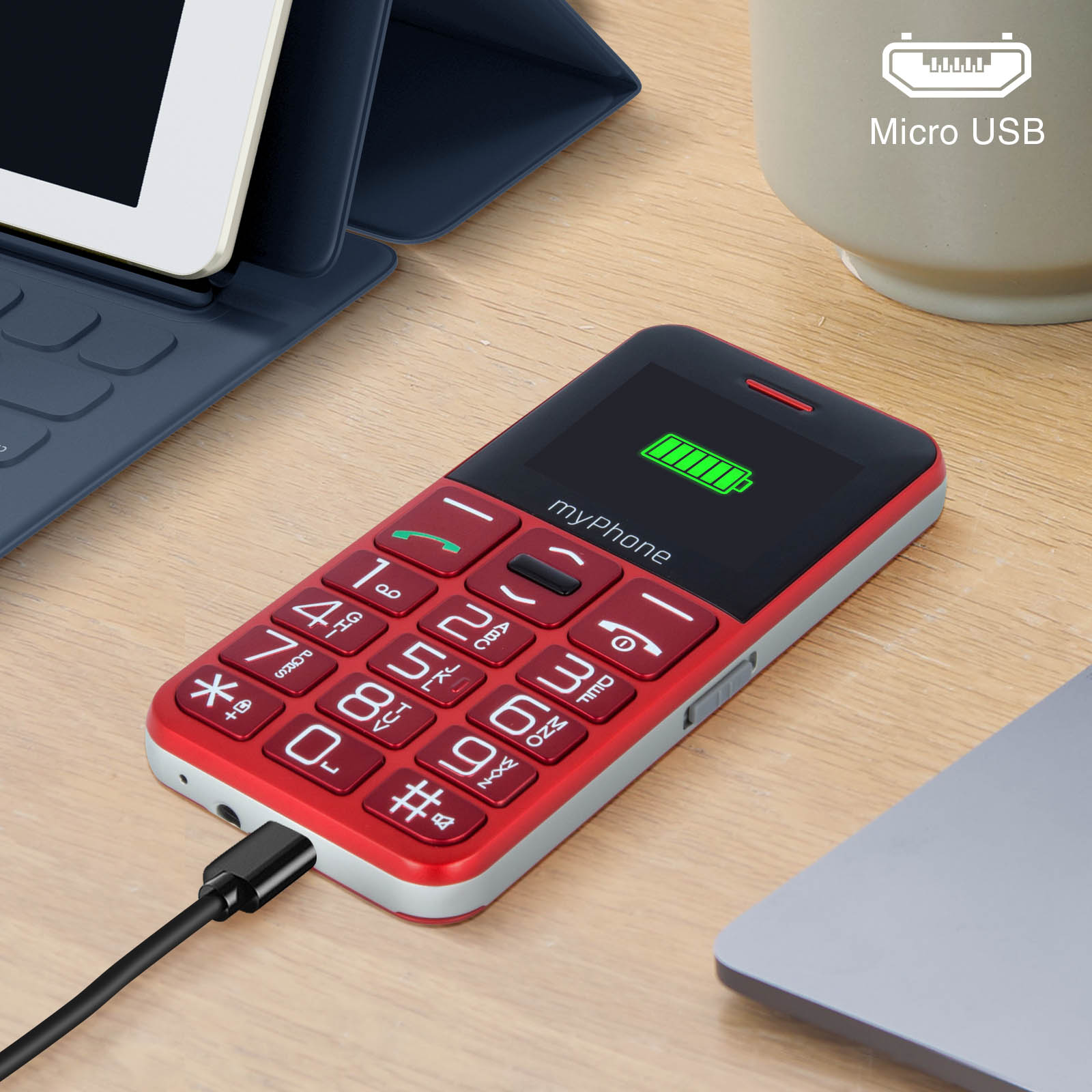 Rotes und weißes myPhone mit angeschlossenem Ladekabel. Tablet und Laptop in der Nähe.