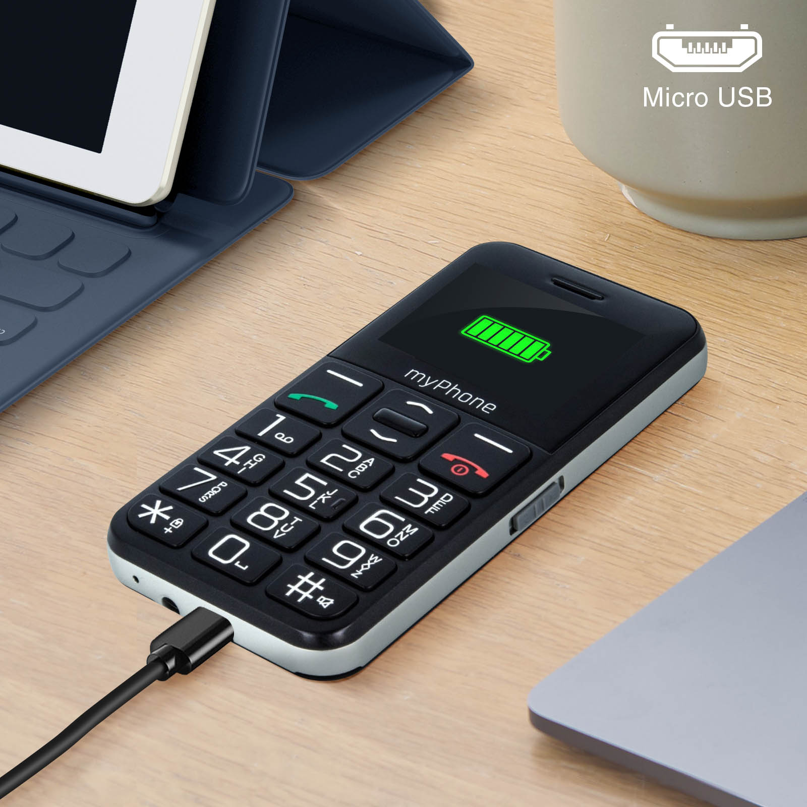 Pequeño myPhone negro con cable de carga, tableta y portátil en el fondo.
