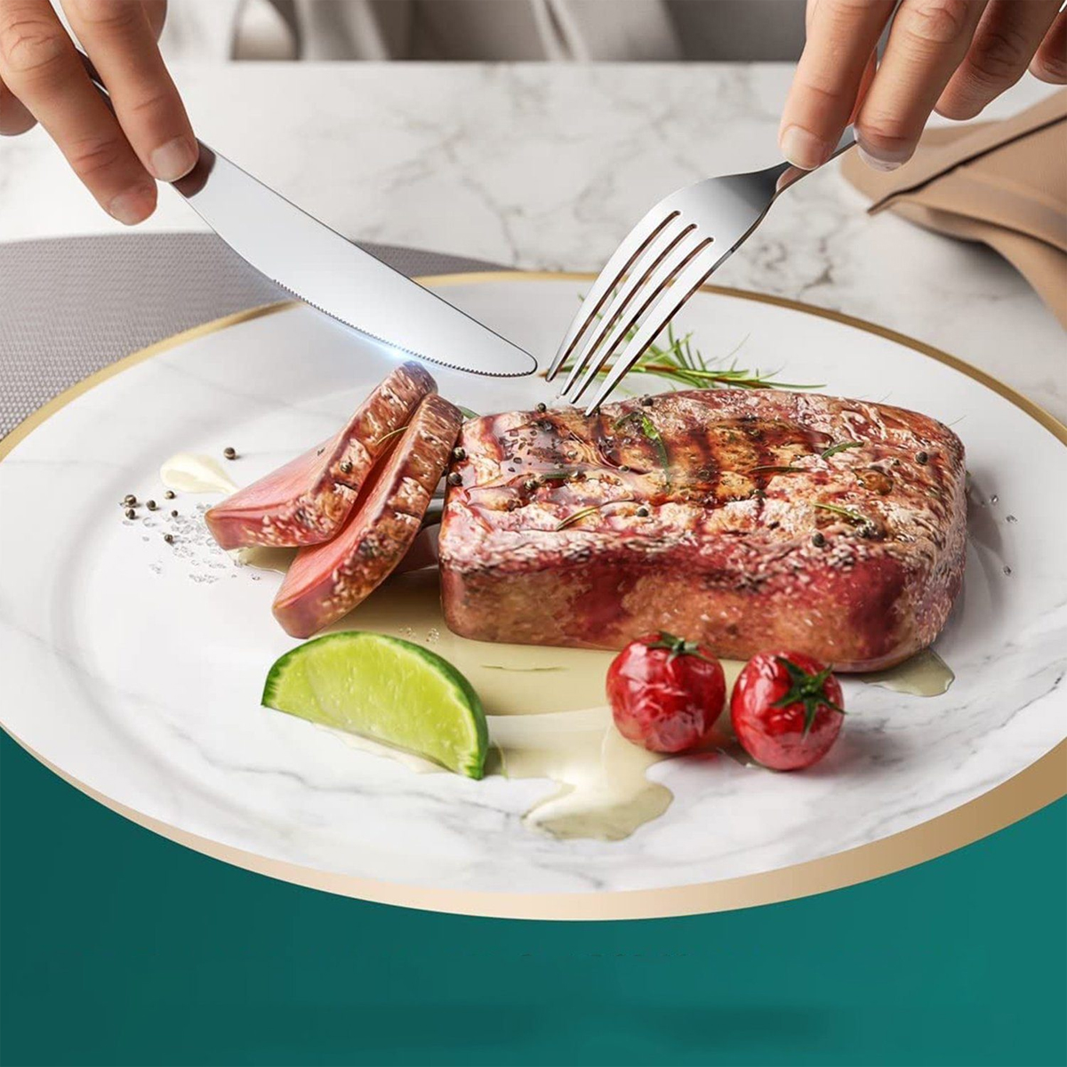 Steak auf Teller mit Händen, die Messer und Gabel benutzen. Limette und Tomaten vorhanden.