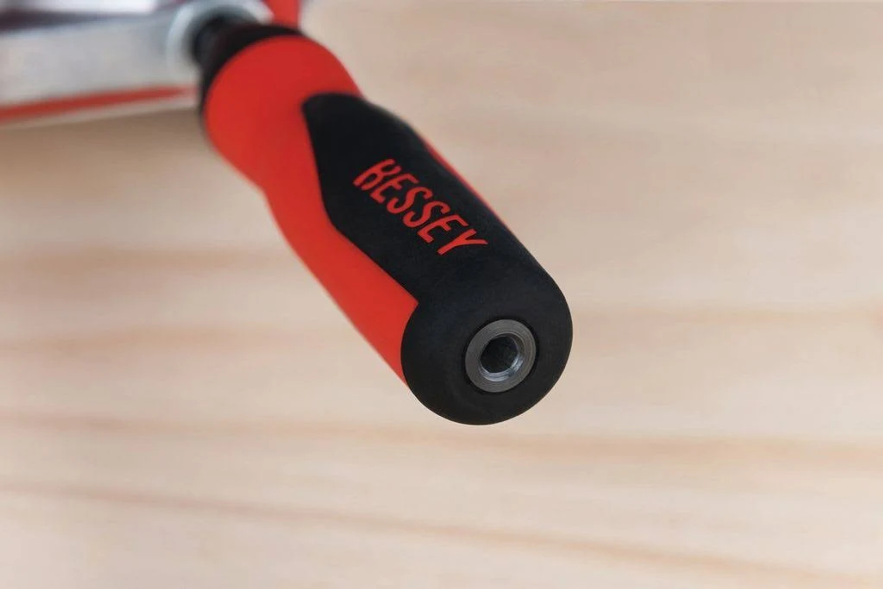 Primer plano de un mango rojo y negro de una abrazadera BESSEY sobre madera.