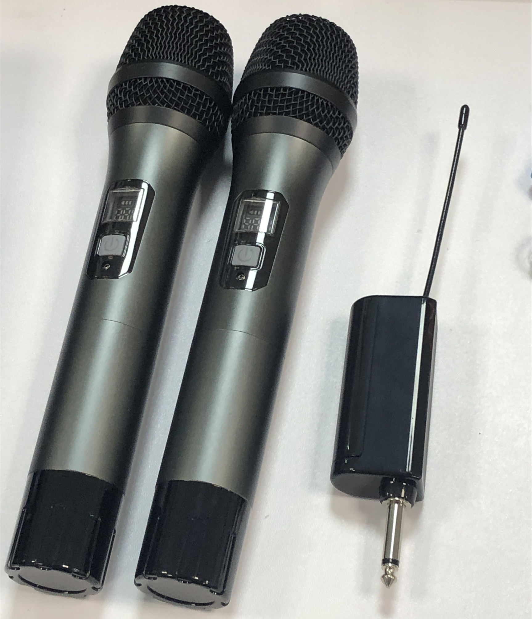 Dwa mikrofony, odbiornik i wtyczka są pokazane na białej powierzchni.