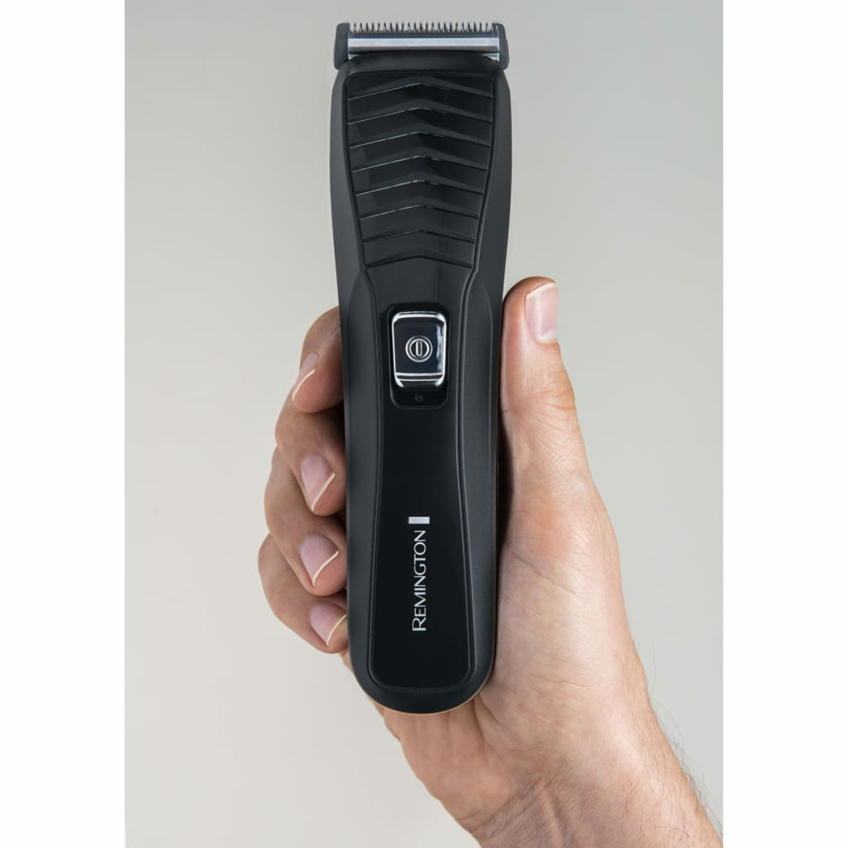 Hand hält schwarzen Haarschneider. Der Trimmer ist eingeschaltet.