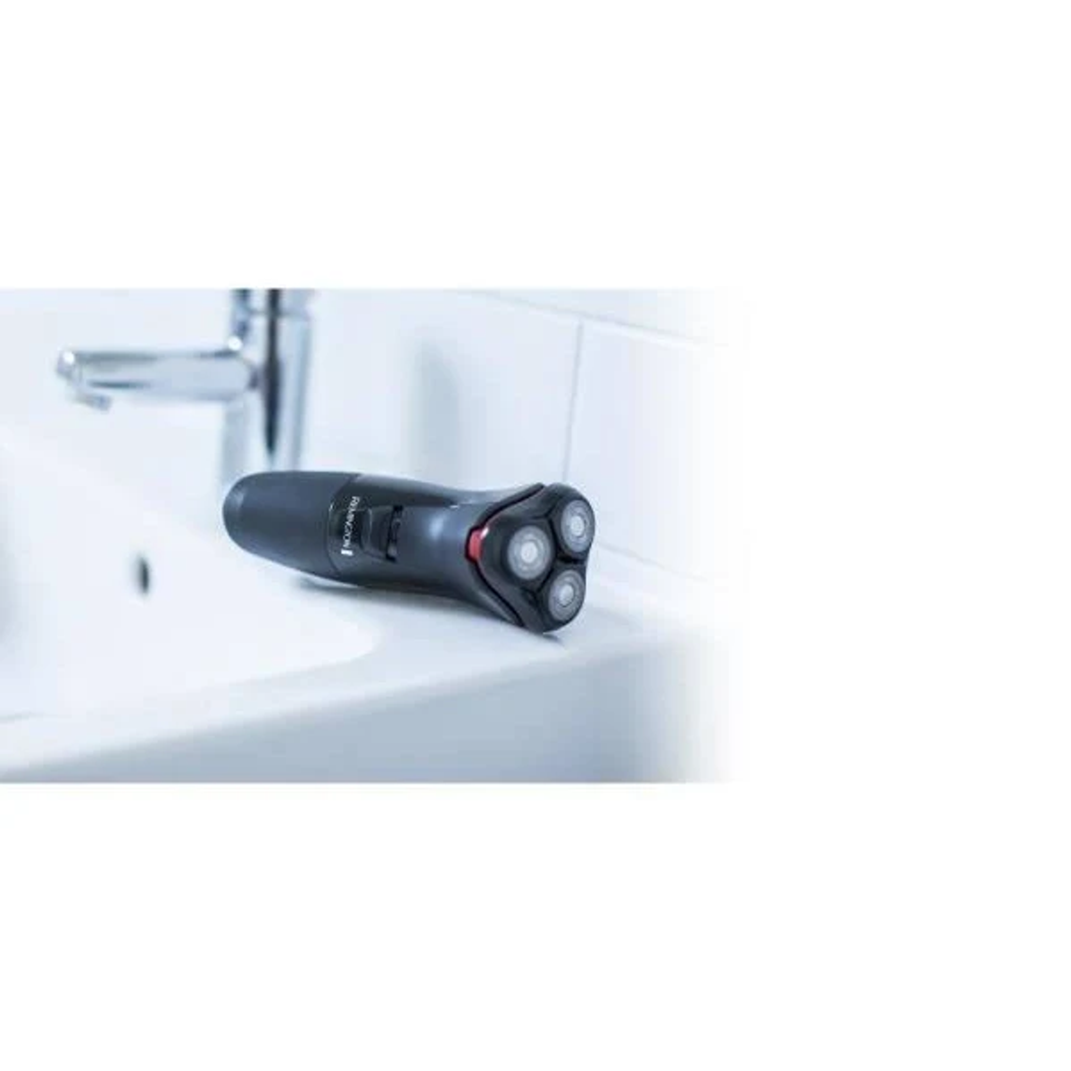 Afeitadora eléctrica Remington negra y gris en un lavabo blanco. La afeitadora tiene tres cabezales rotatorios.