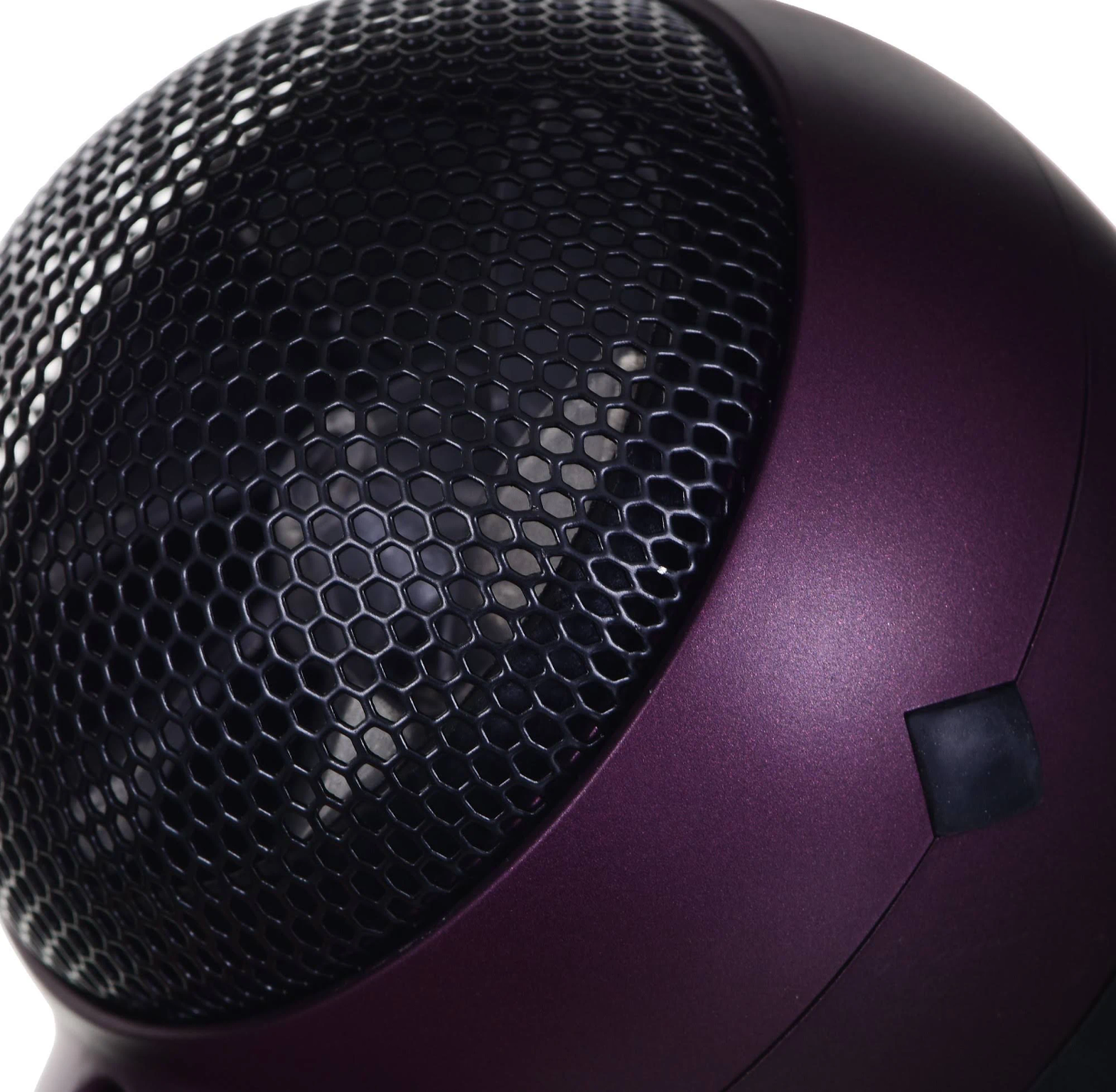 Fioletowy głośnik z czarną siatką. Białe tło.