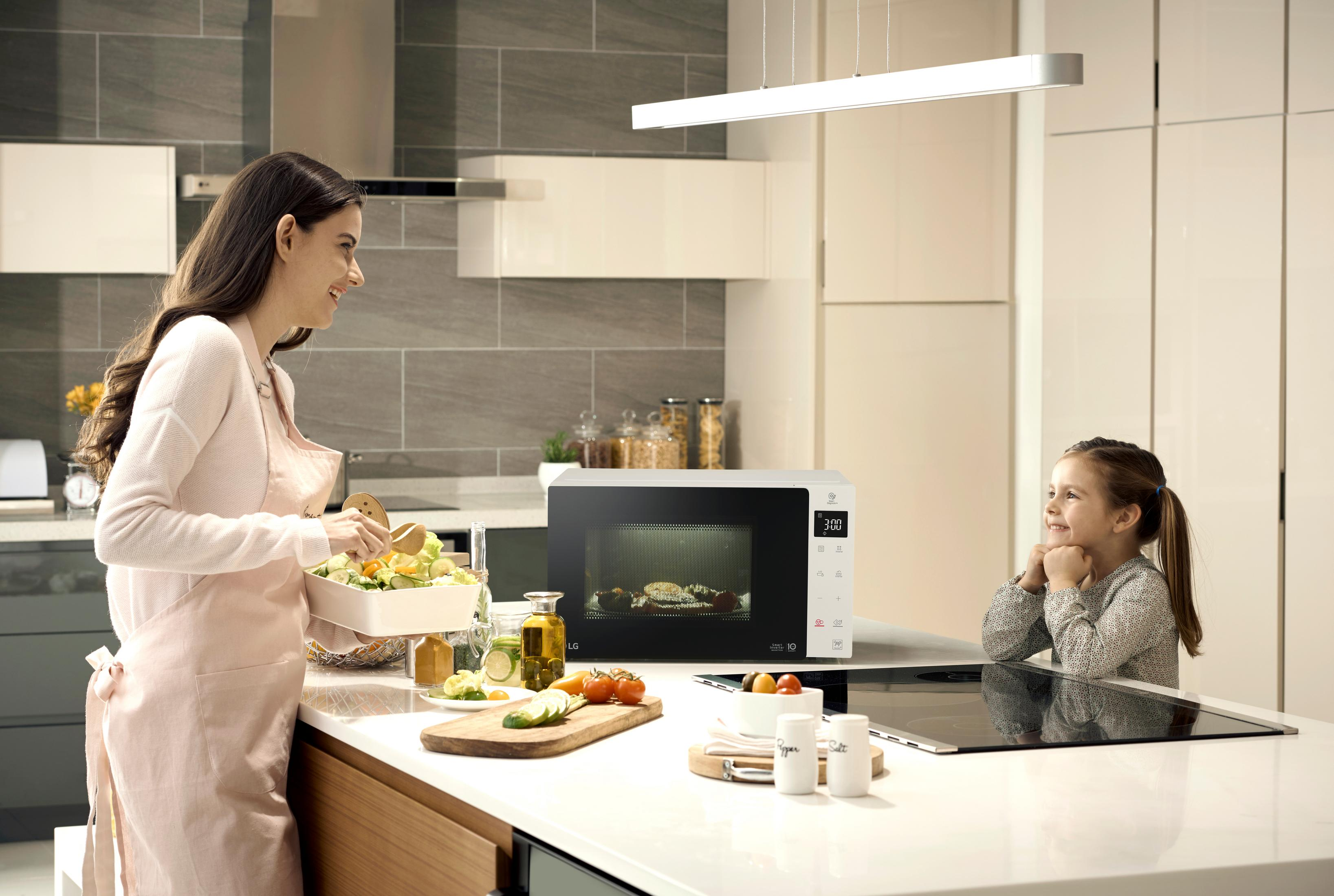 Une femme et une fille dans une cuisine avec un micro-ondes. La femme prépare de la nourriture.