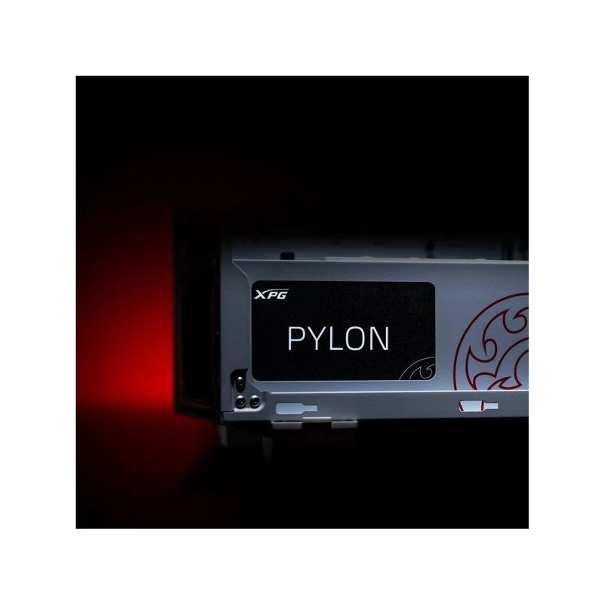 Srebrny dysk SSD z etykietą 'PYLON'. Logo XPG. Czerwone tło.