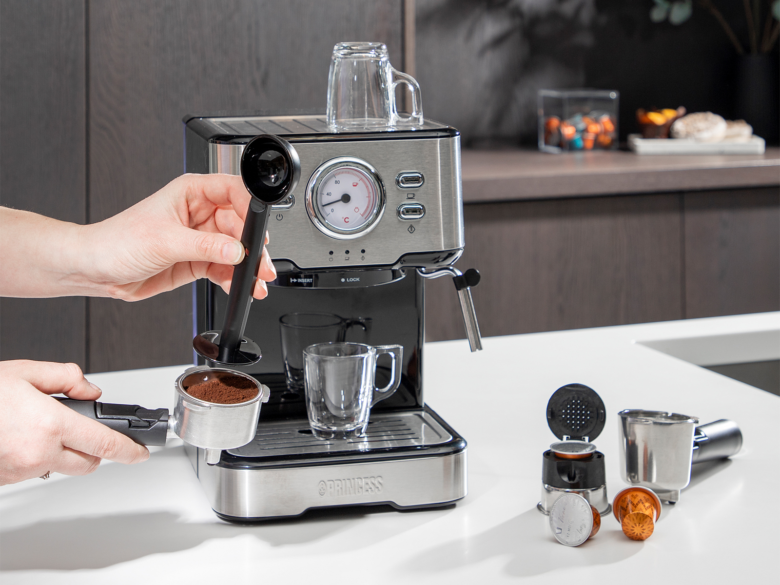 Espressomaschine mit Zubehör, Hand hält Schaufel. Weißer Hintergrund.