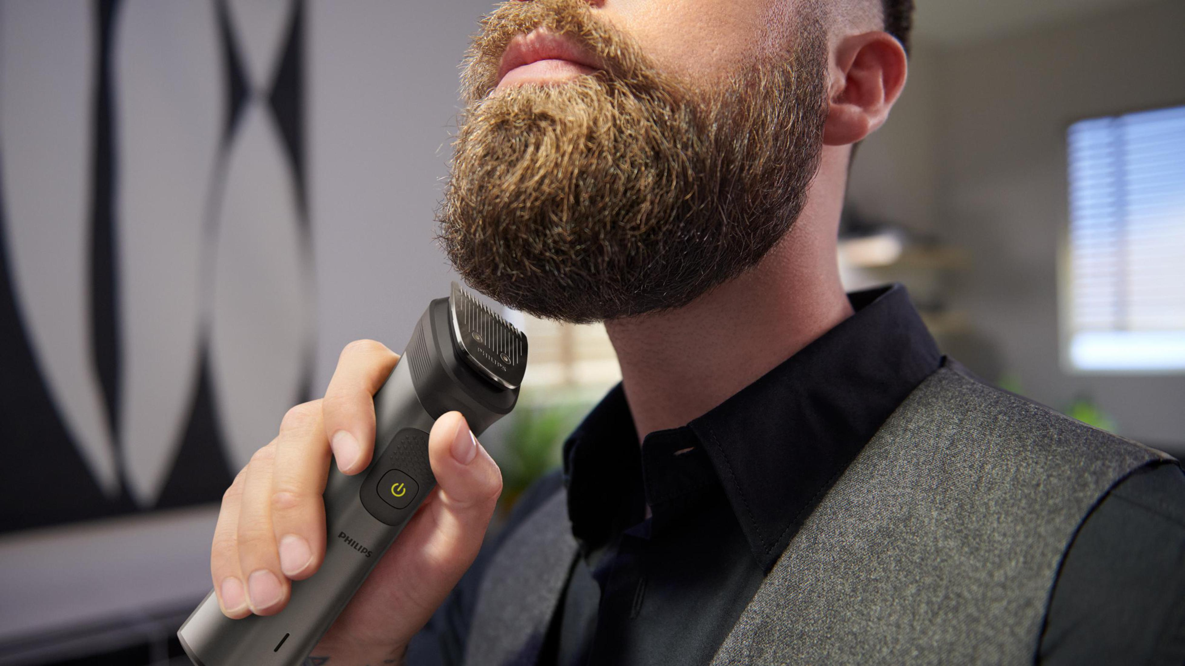 Un hombre recortando su barba con una recortadora, mostrando la recortadora y la barba.