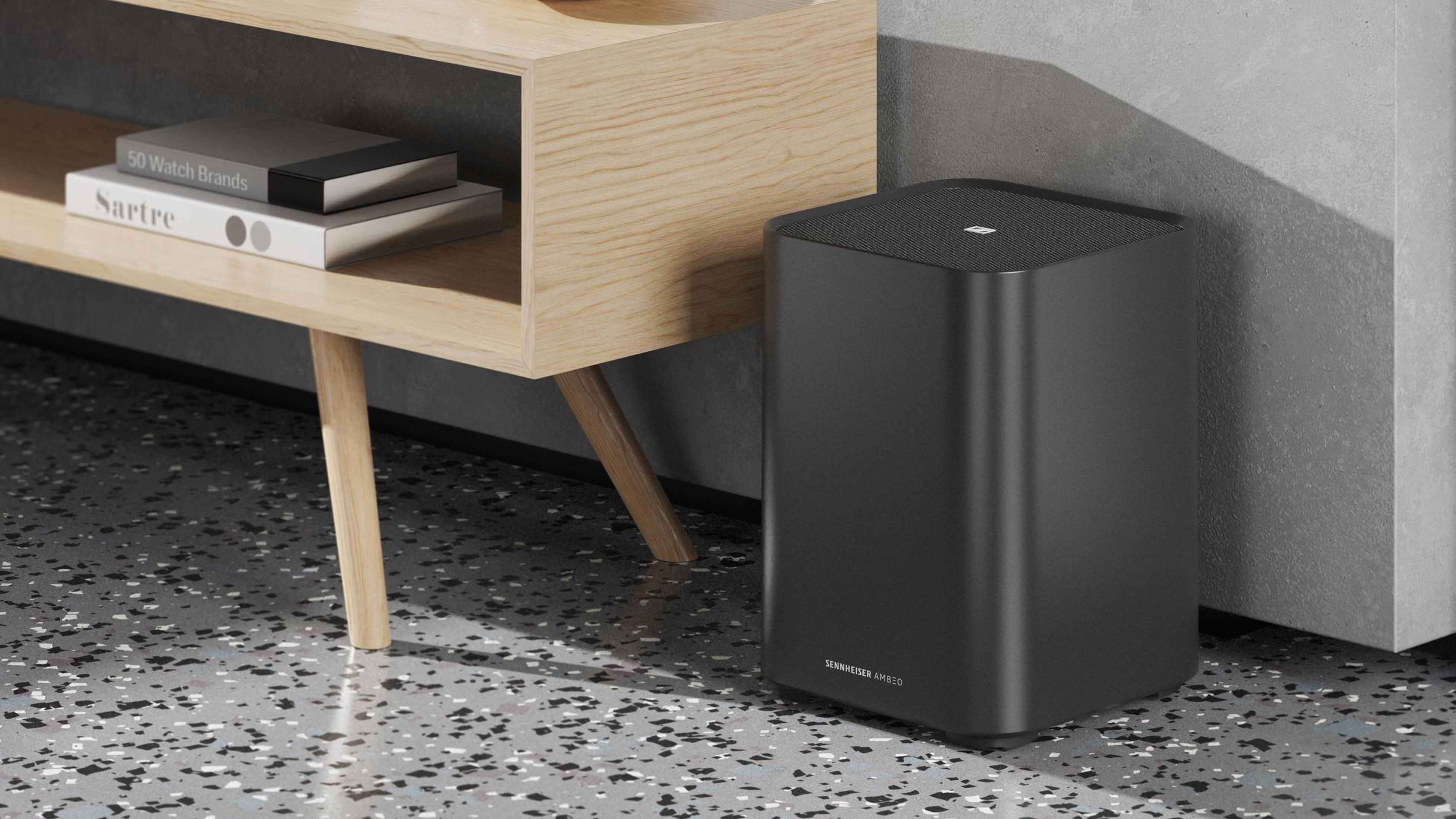 Schwarzer Subwoofer-Lautsprecher auf dem Boden neben einem Holzregal und einer weißen Wand.
