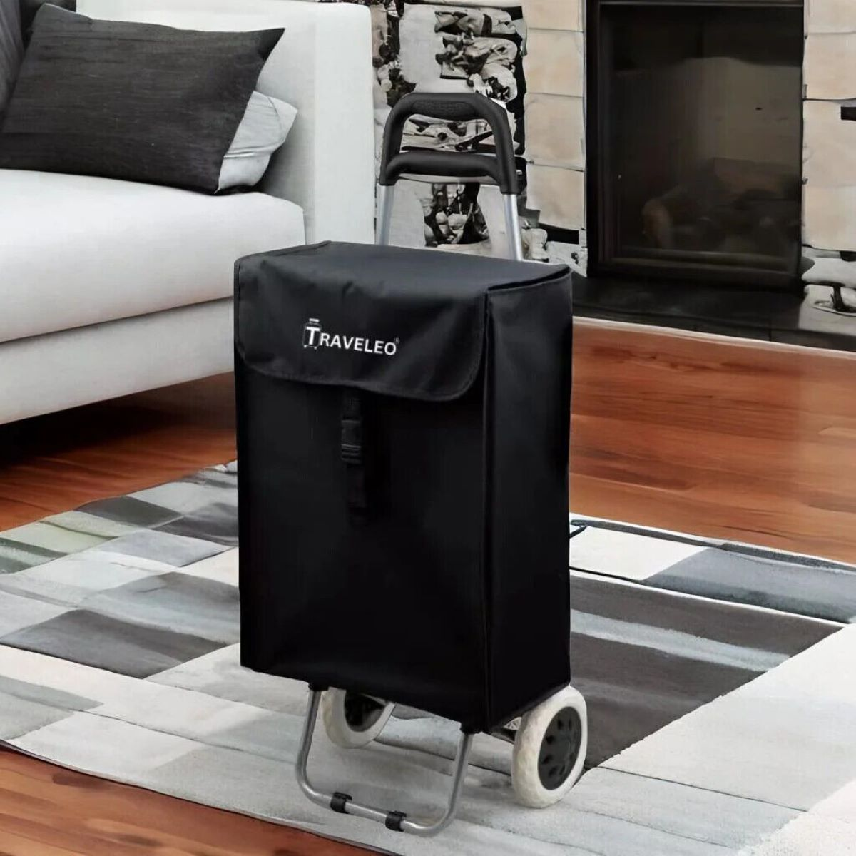 Schwarzer Einkaufswagen mit schwarzer Tasche auf einem gemusterten Teppich vor einem Sofa.