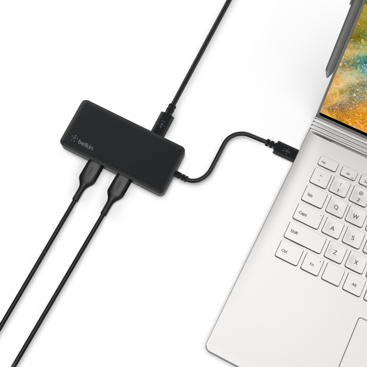 Een Belkin USB-hub aangesloten op een laptop en andere kabels.