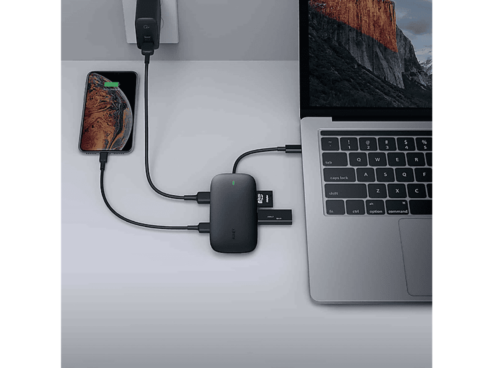 Laptop und Telefon laden. Schwarzer Hub mit USB- und SD-Karten-Anschlüssen ist angeschlossen.