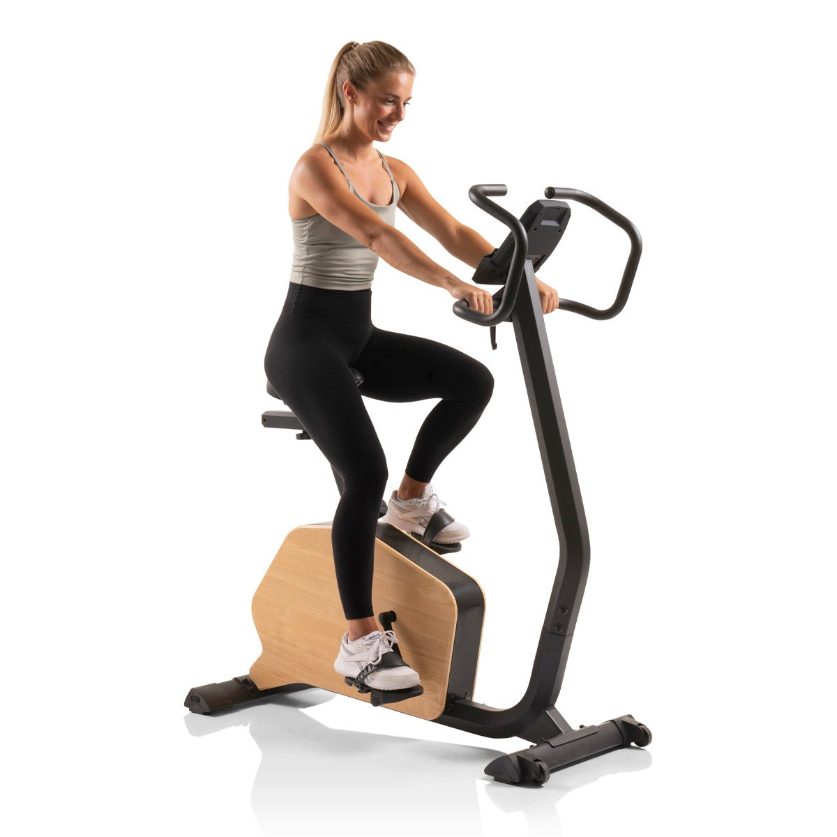 Frau, die auf einem Heimtrainer trainiert, lächelt in heller Umgebung.