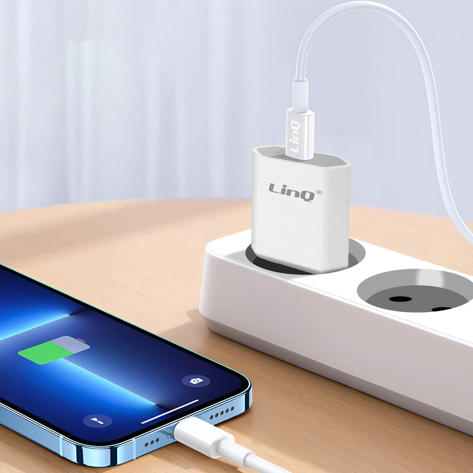 Un cargador blanco está enchufado a una regleta. Un teléfono se está cargando. El teléfono es azul.