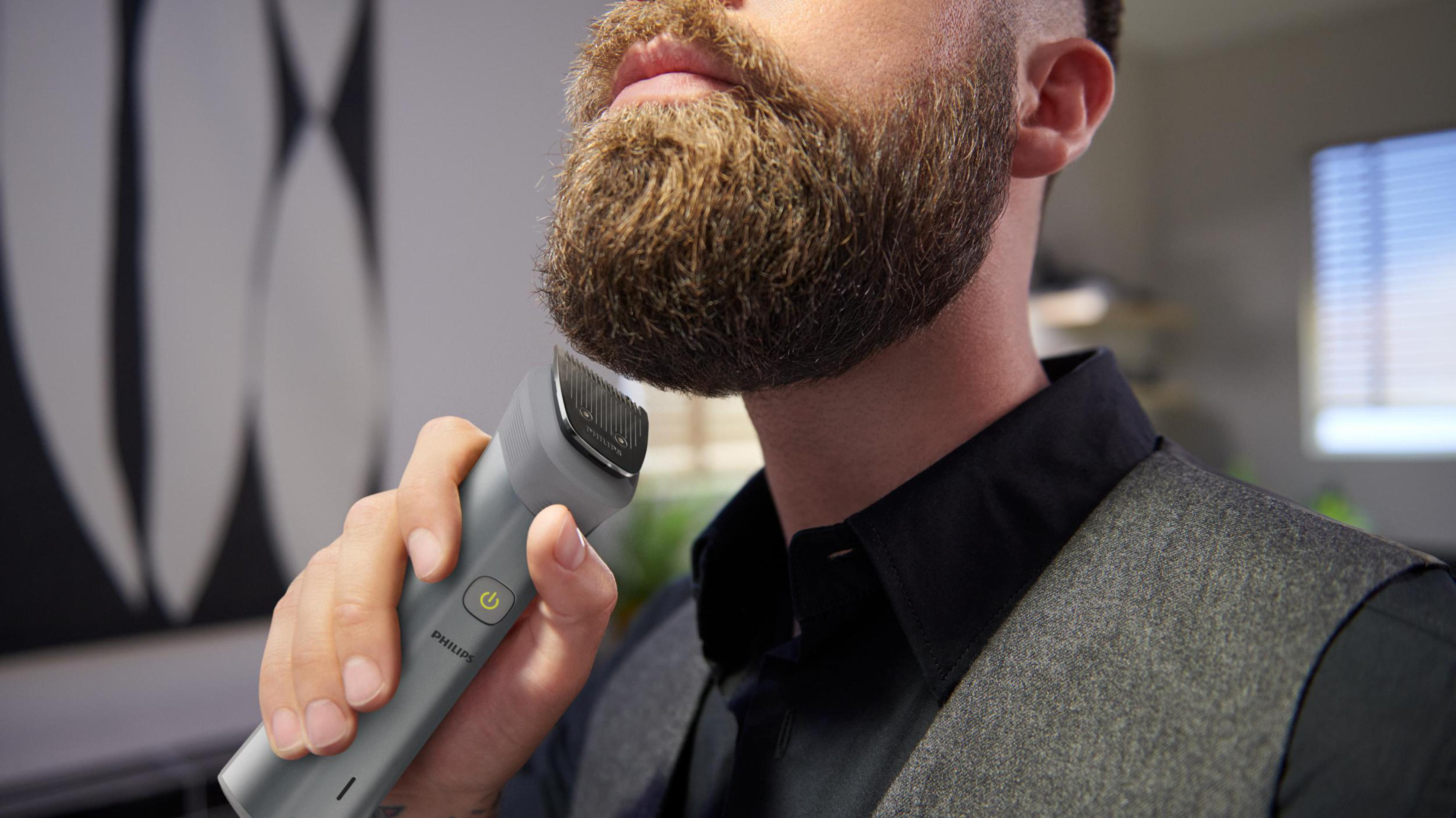 Mann rasiert Bart mit grauem Philips Trimmer, Nahaufnahme.