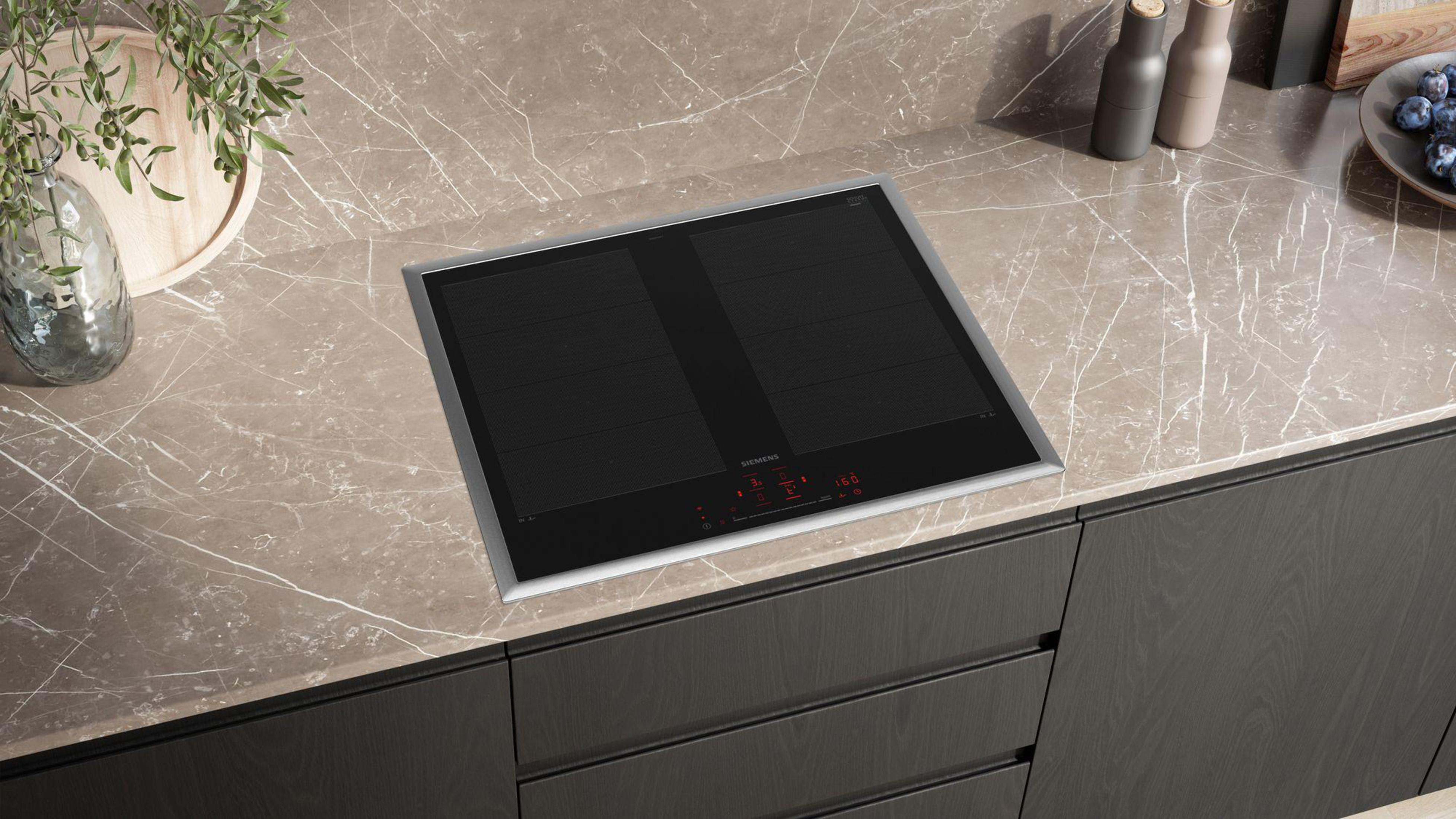 Nowoczesna, wbudowana, czarna płyta indukcyjna na jasnobrązowym blacie, ciemne szafki.