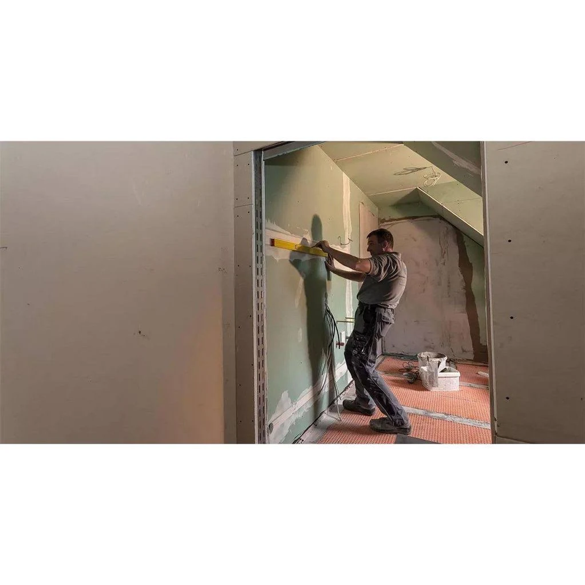 Mann, der eine Wand mit einem Werkzeug ausrichtet, Innenaufnahme.