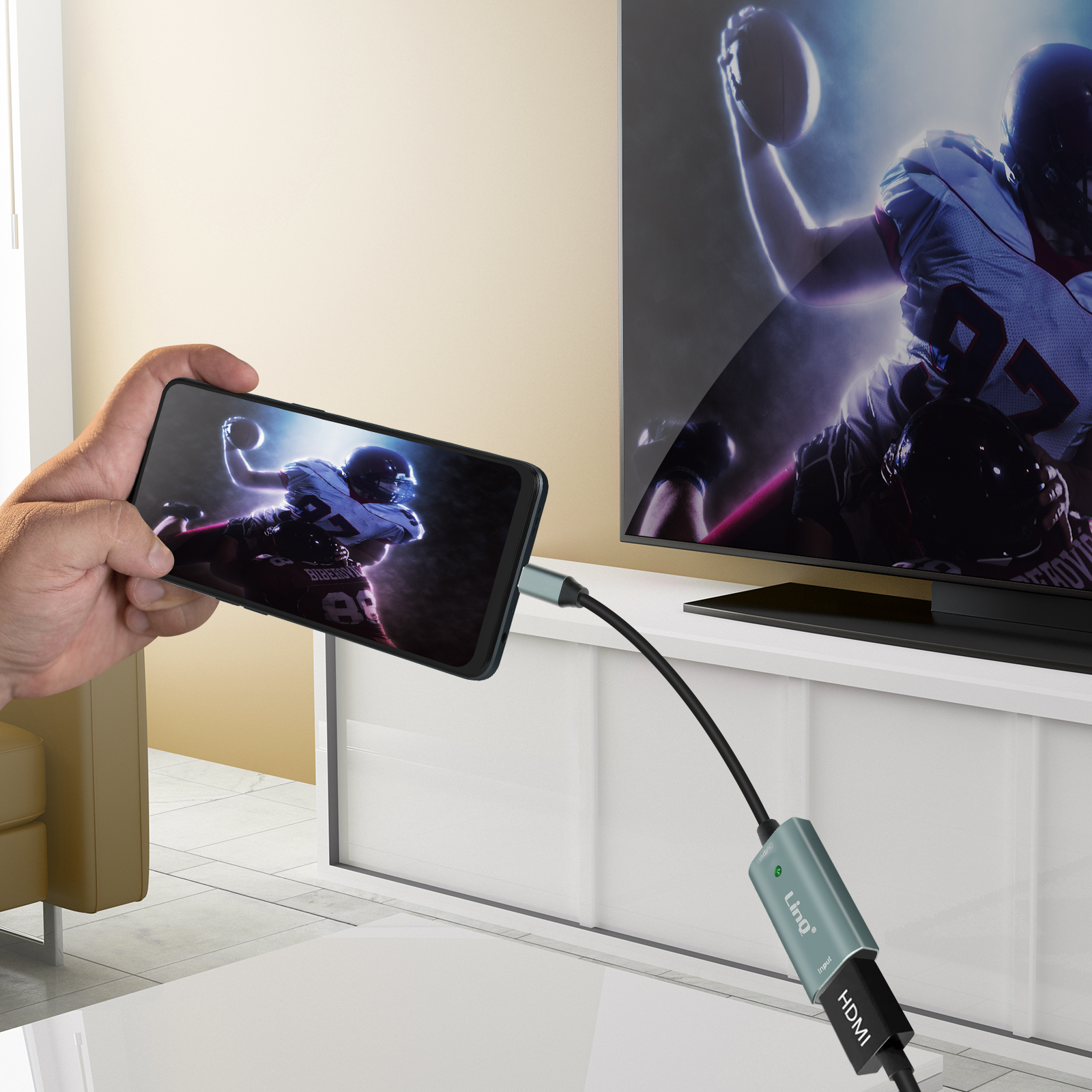 Una persona tiene in mano un telefono che mostra una partita di calcio, collegato a uno schermo tramite HDMI.
