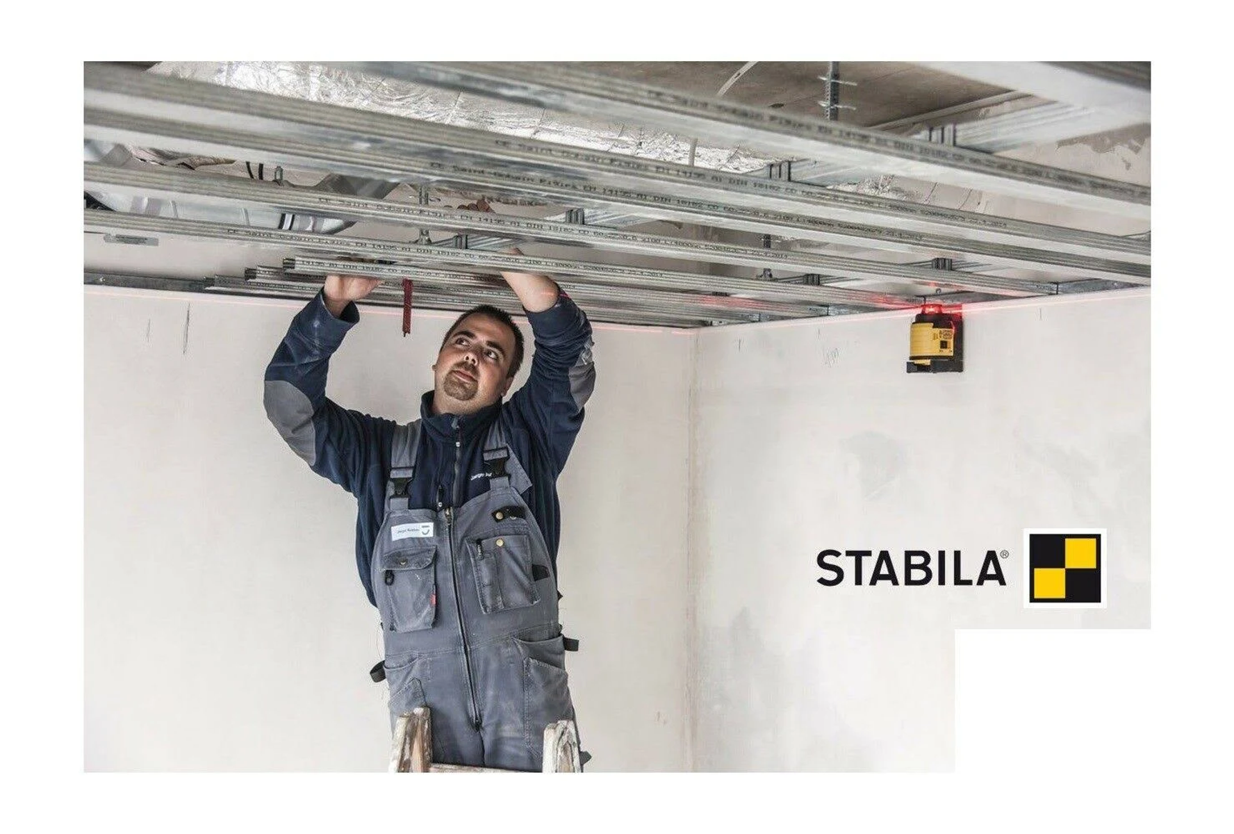 Mann installiert einen Laser-Wasserwaage an der Decke, STABILA-Logo.