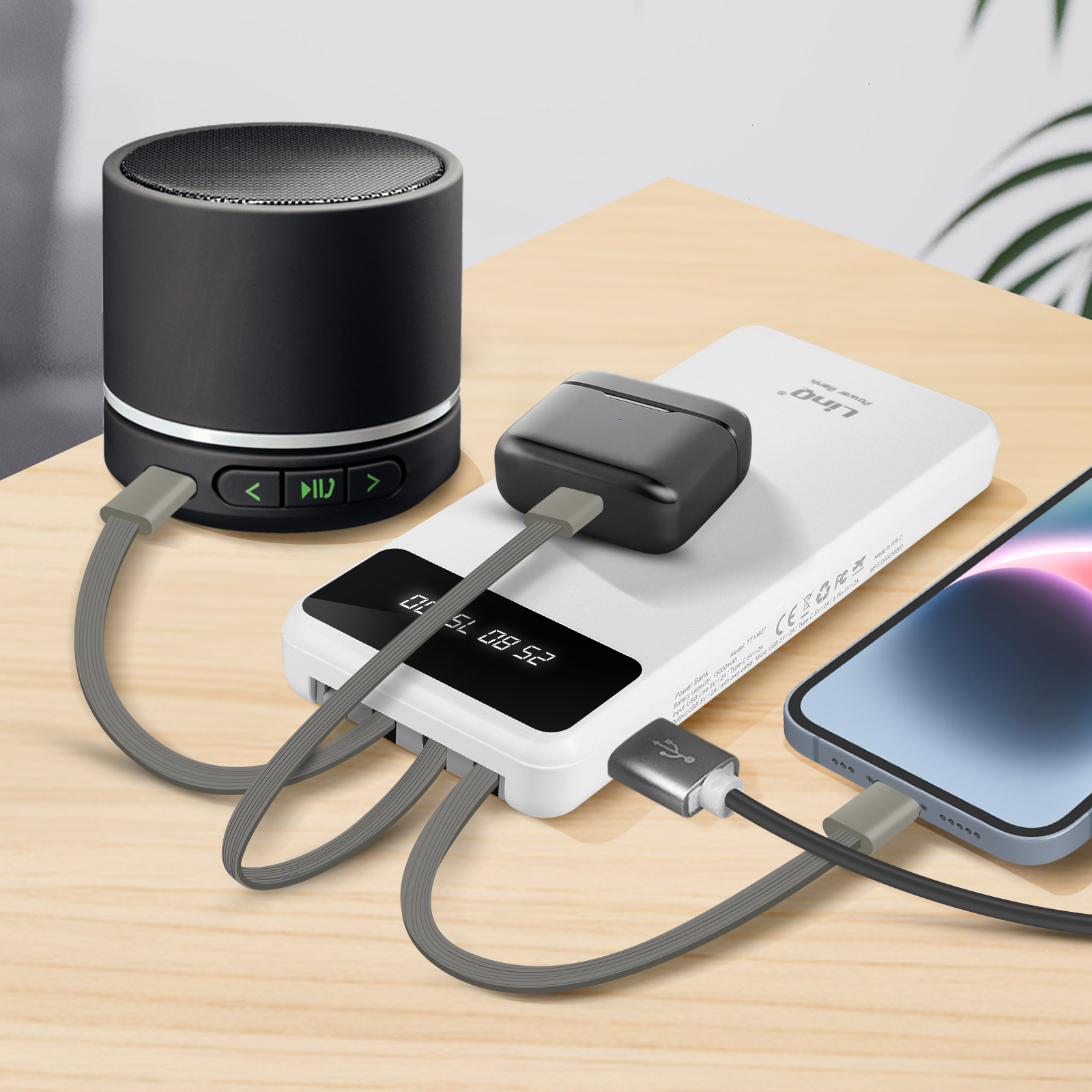 Téléphone portable, haut-parleur et station de charge. Tous sont connectés avec des câbles gris. Table en bois.